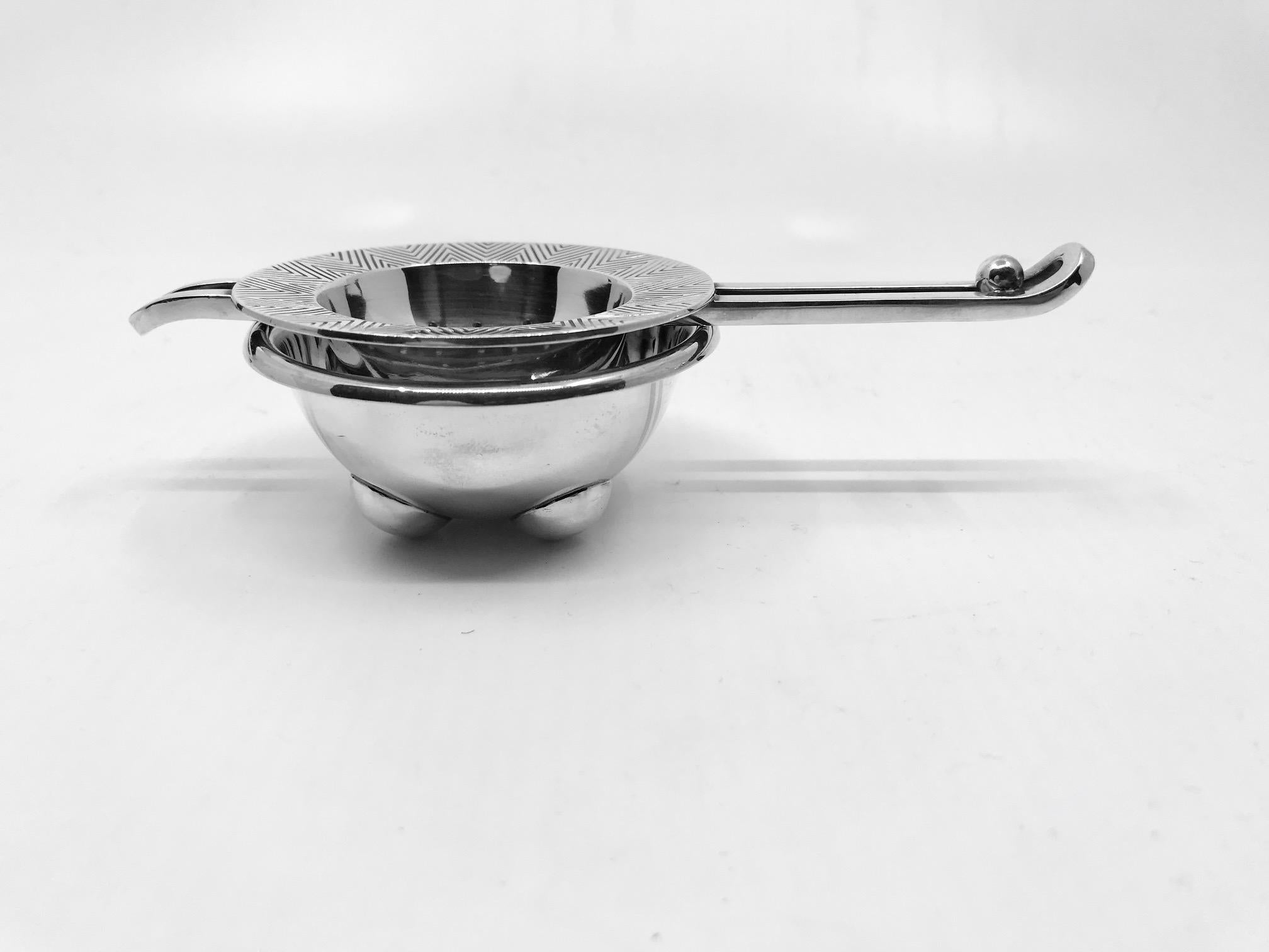 This is a sterling silver Hans Hansen Art Deco tea strainer and stand (drip bowl), design by Karl Gustav Hansen.

The strainer measures 5 7/8? in length, external diameter 2 3/4?, internal diameter 1 7/8? (14.7cm, 7.1cm, 4.8cm).

The stand/drip