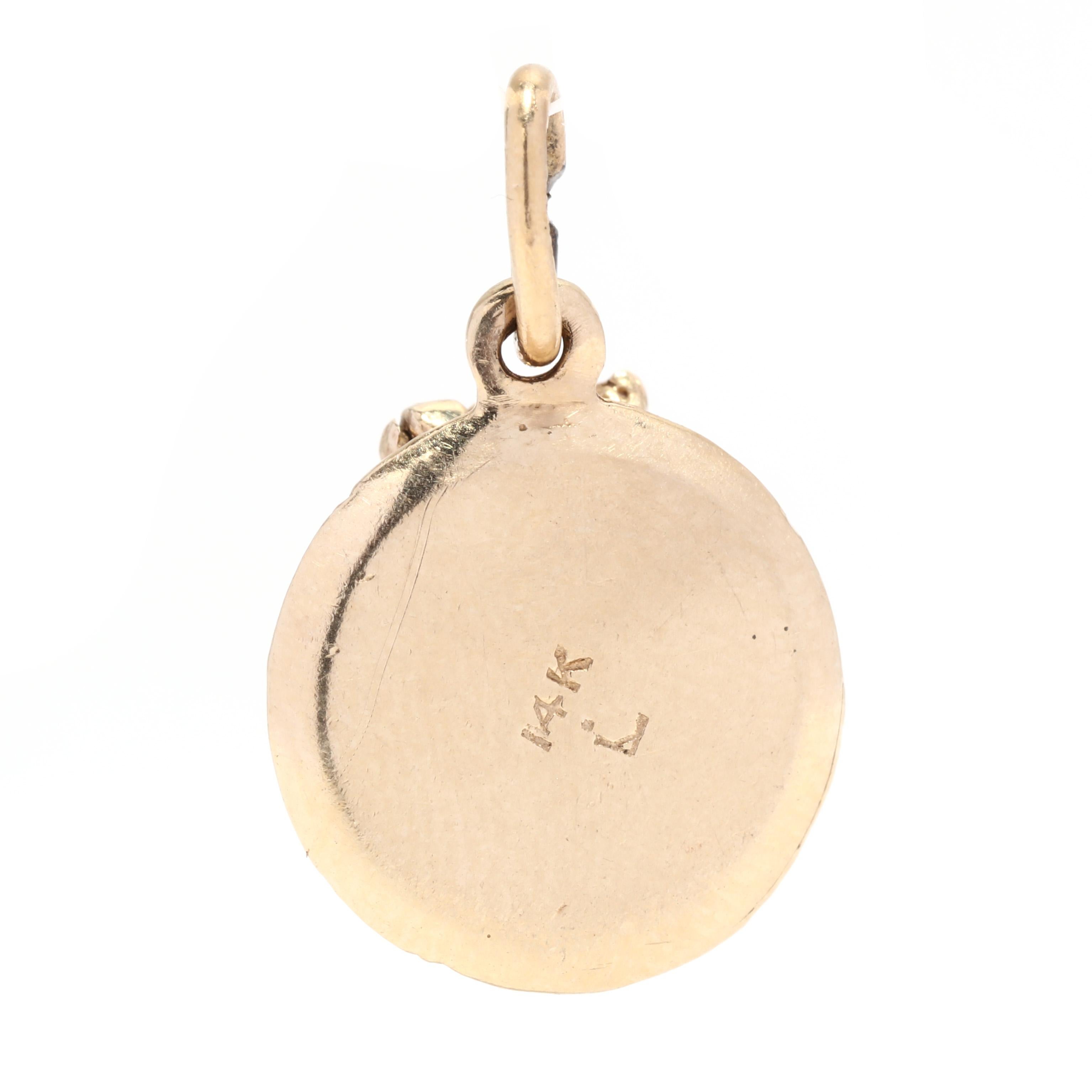 A vintage 14 karat yellow gold 'Happy Anniversary' enamel cake charm. This small gold charm features a round shape with applied detailing including 'Happy Anniversary' surrounded by white enamel, with an articulated top that opens to reveal a hidden