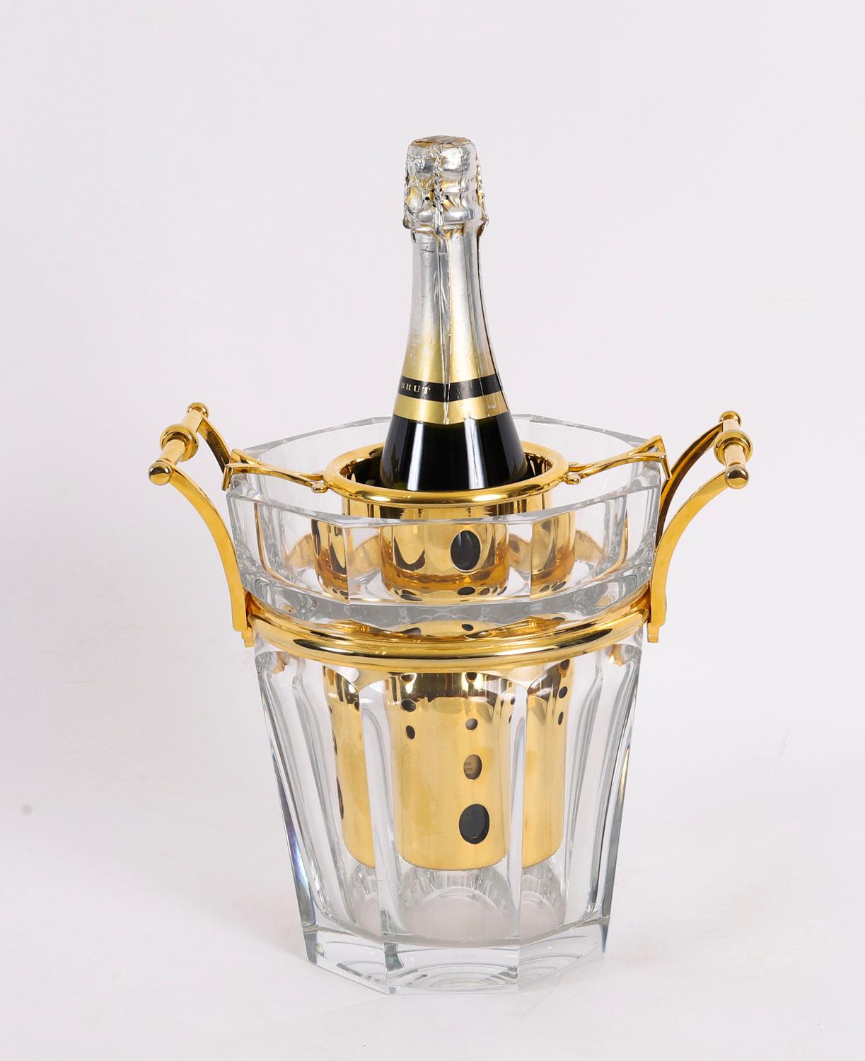 Un favoloso dispenser per champagne Baccarat 'Harcourt' in cristallo e placcato oro, risalente agli anni '70.

Il secchiello ottagonale e affusolato in cristallo presenta un marchio Baccarat inciso all'acido sul lato inferiore e due manici a spirale