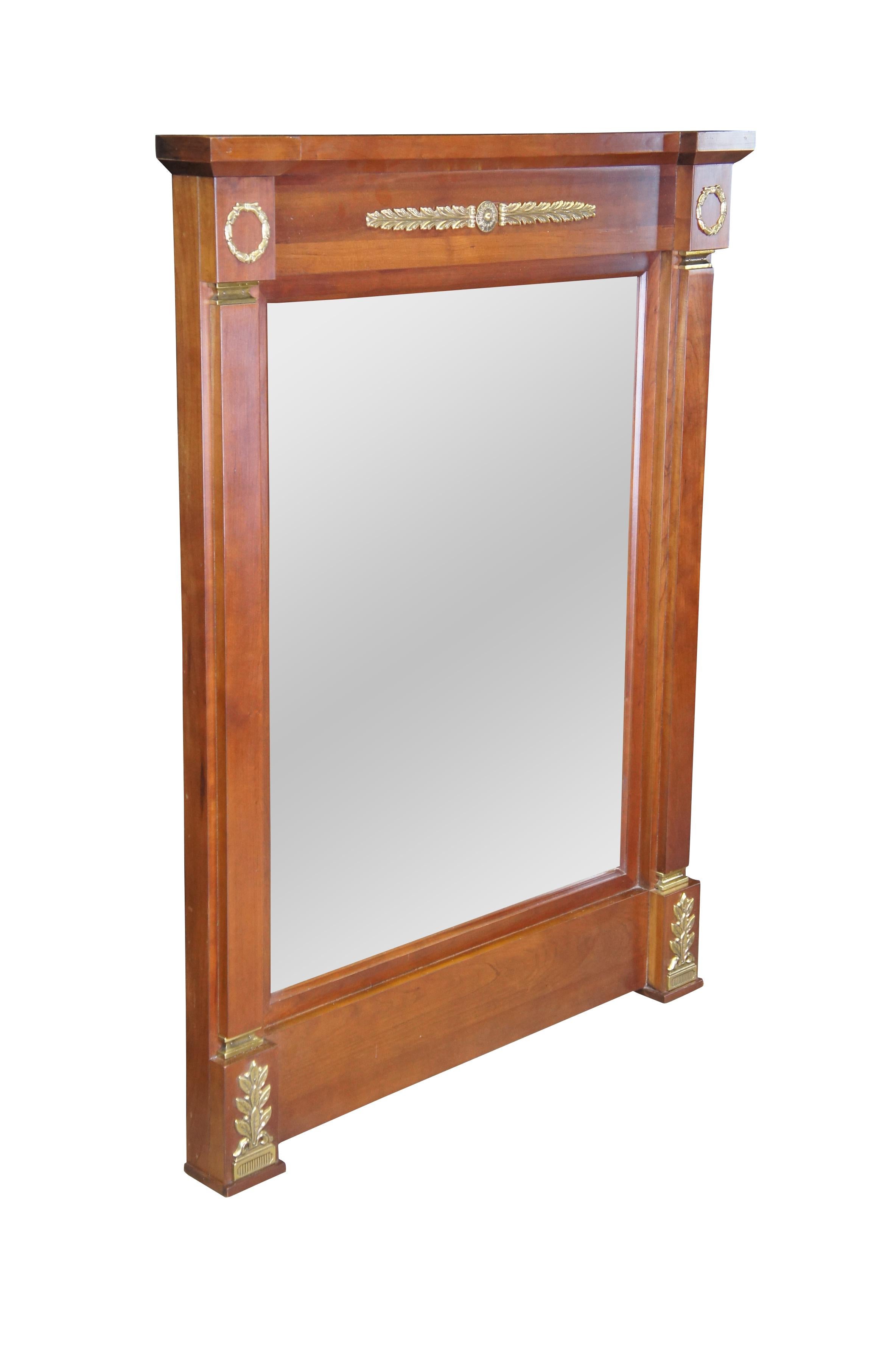 An elegant French Empire style wall hanging or over mantel mirror by Harden Furniture, circa 1980s.  Made from solid cherry with tapered columns, Neoclassical ormolu mounts and beveled plate glass.  

Harden was founded in 1844 by Charles S. Harden.