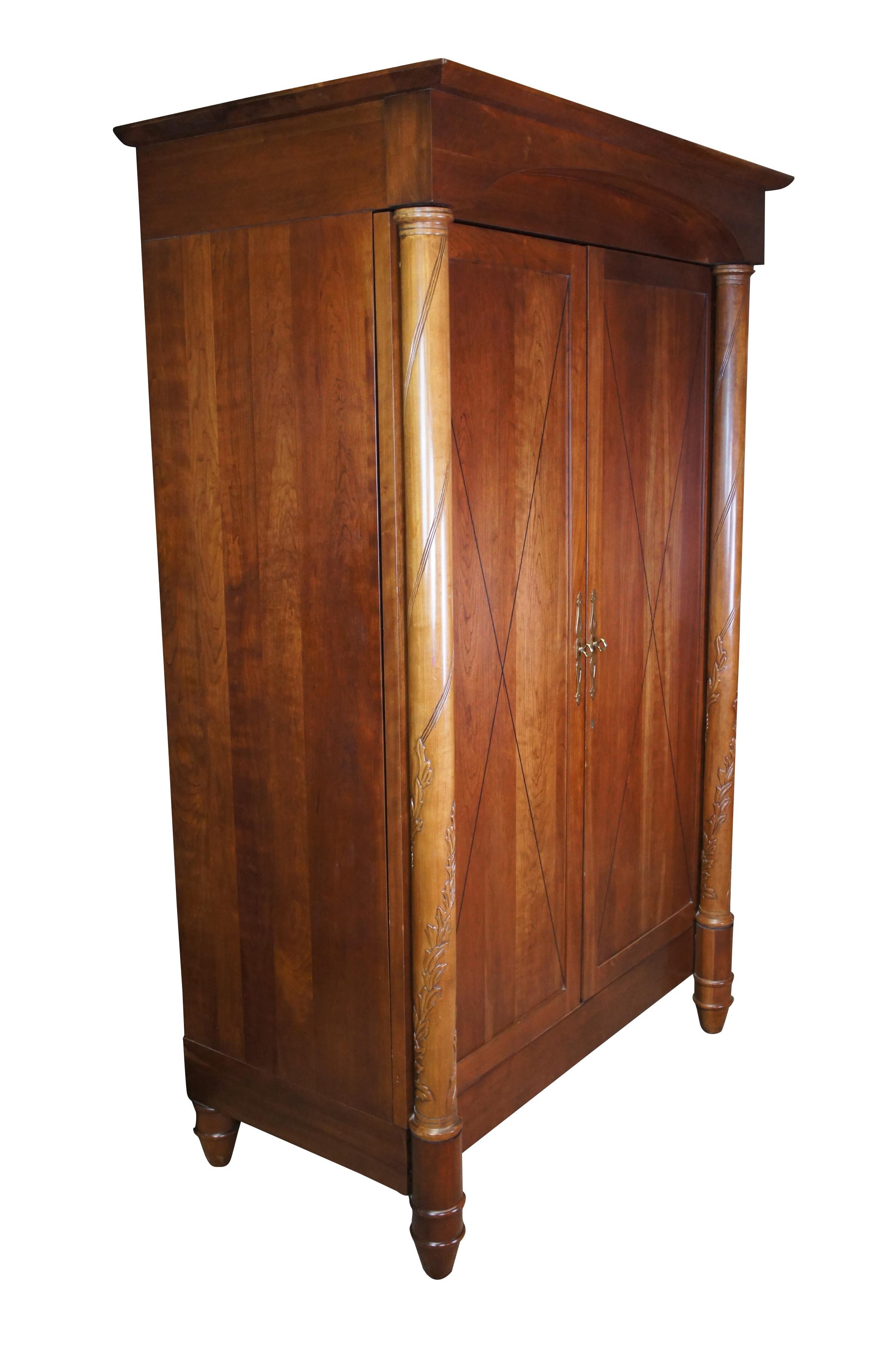 An exceptional wardrobe by Harden Furniture; circa 1980s.  Drawing inspiration from Italian and Neoclassical styling.  Made from solid Cherry with double doors set behind acanthus carved and spiral fluted columns.  The doors feature classic X inlay