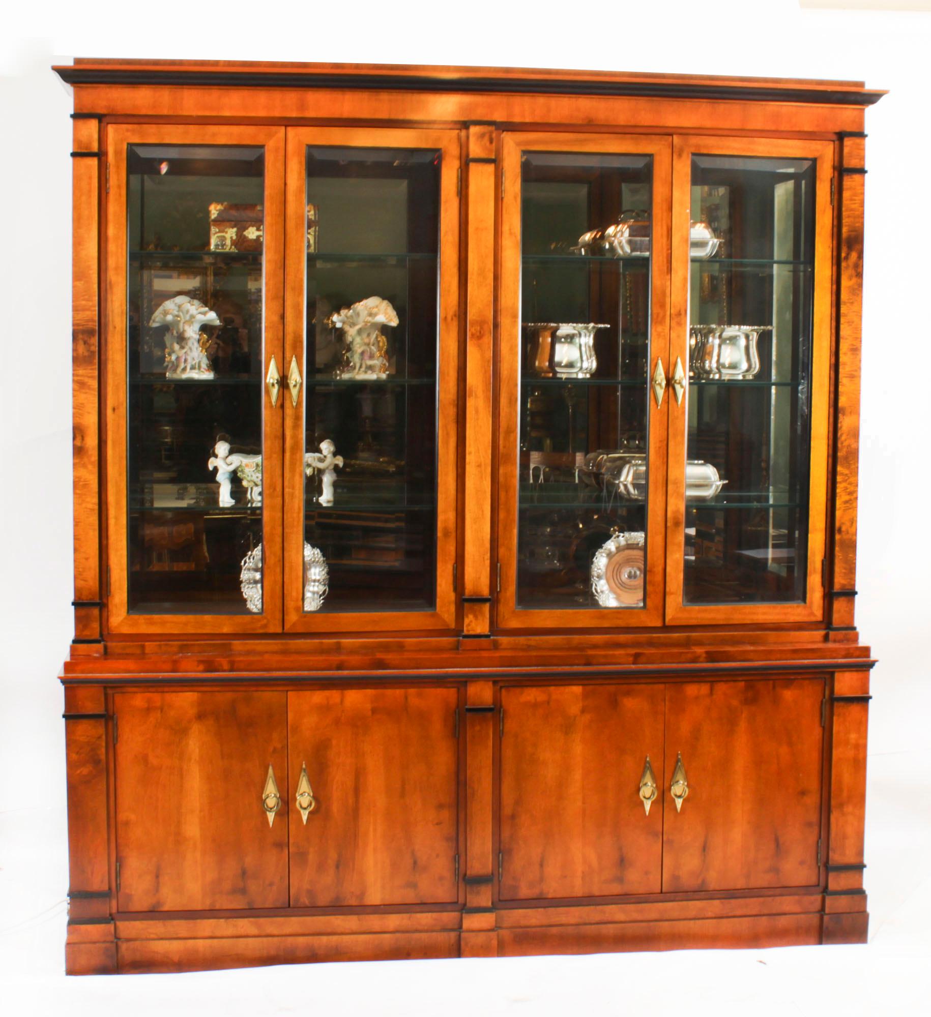 This is an elegant vintage Biedermeier Revival satin birch collectors bookcase purchased at great expense from Harrods, circa 1980 in date.

The top features four glazed bevelled doors, each opens to reveal three adjustable glass shelves. The