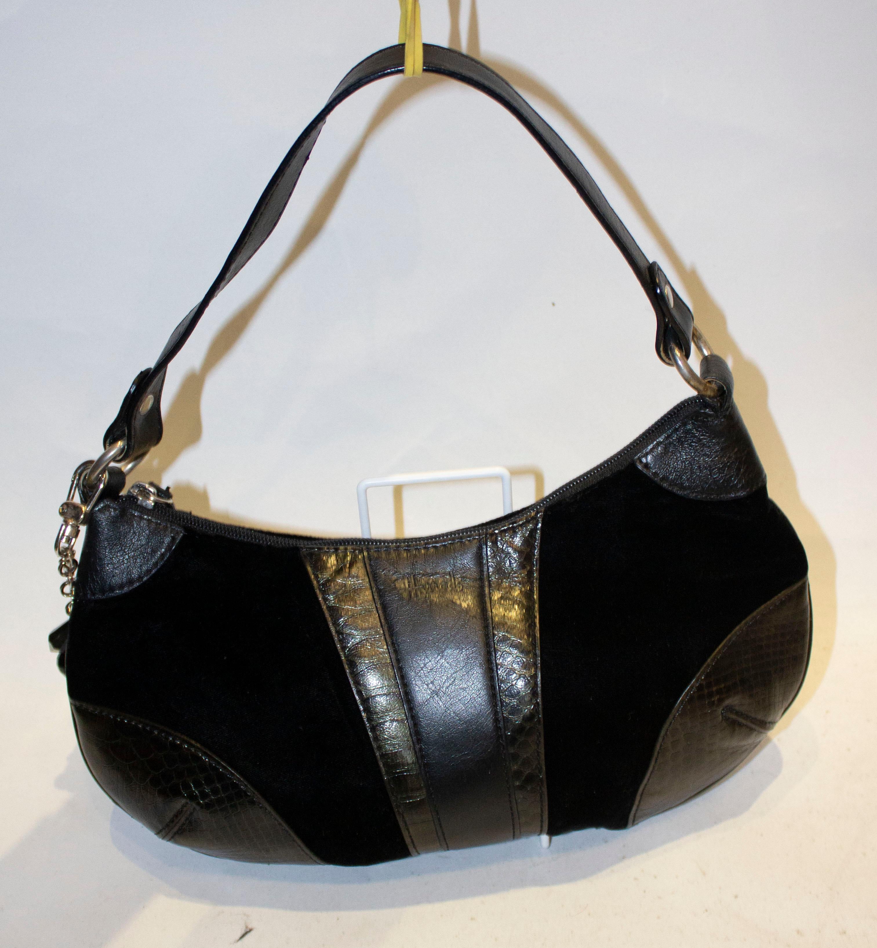 A chic vintage handbg by Harrods. The bag is made of black velvet with  snakeskin and leather trim. It has an internal zip pocket and top zip opening. The shoulder strap measures 18''.