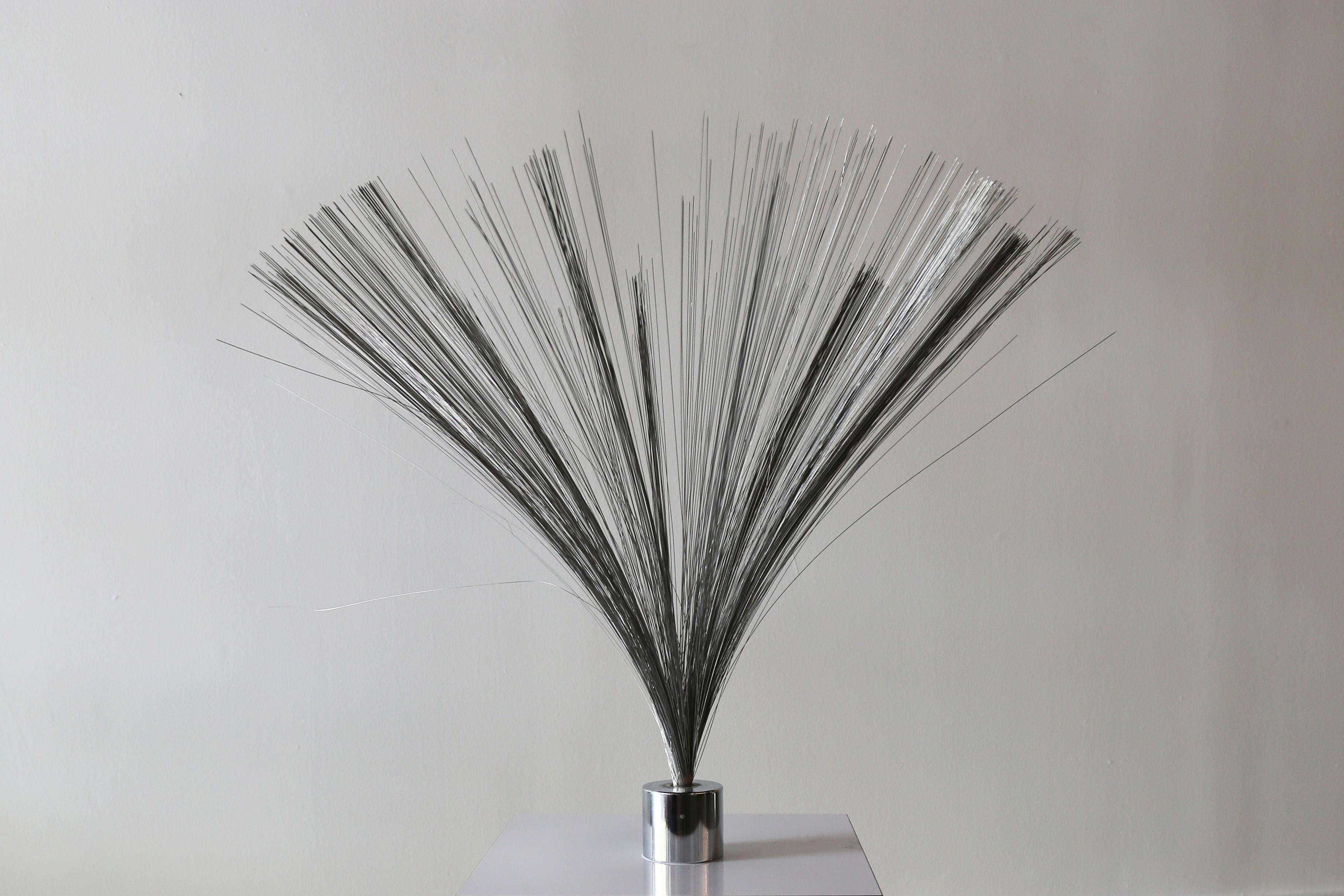 A Harry Bertoia style spray sculpture consisting of a chrome weighted base and a spray of light chrome wire kinetic strands suspended above. The light strands bounce and sway in the wind. When brought together and released the strands bounce and