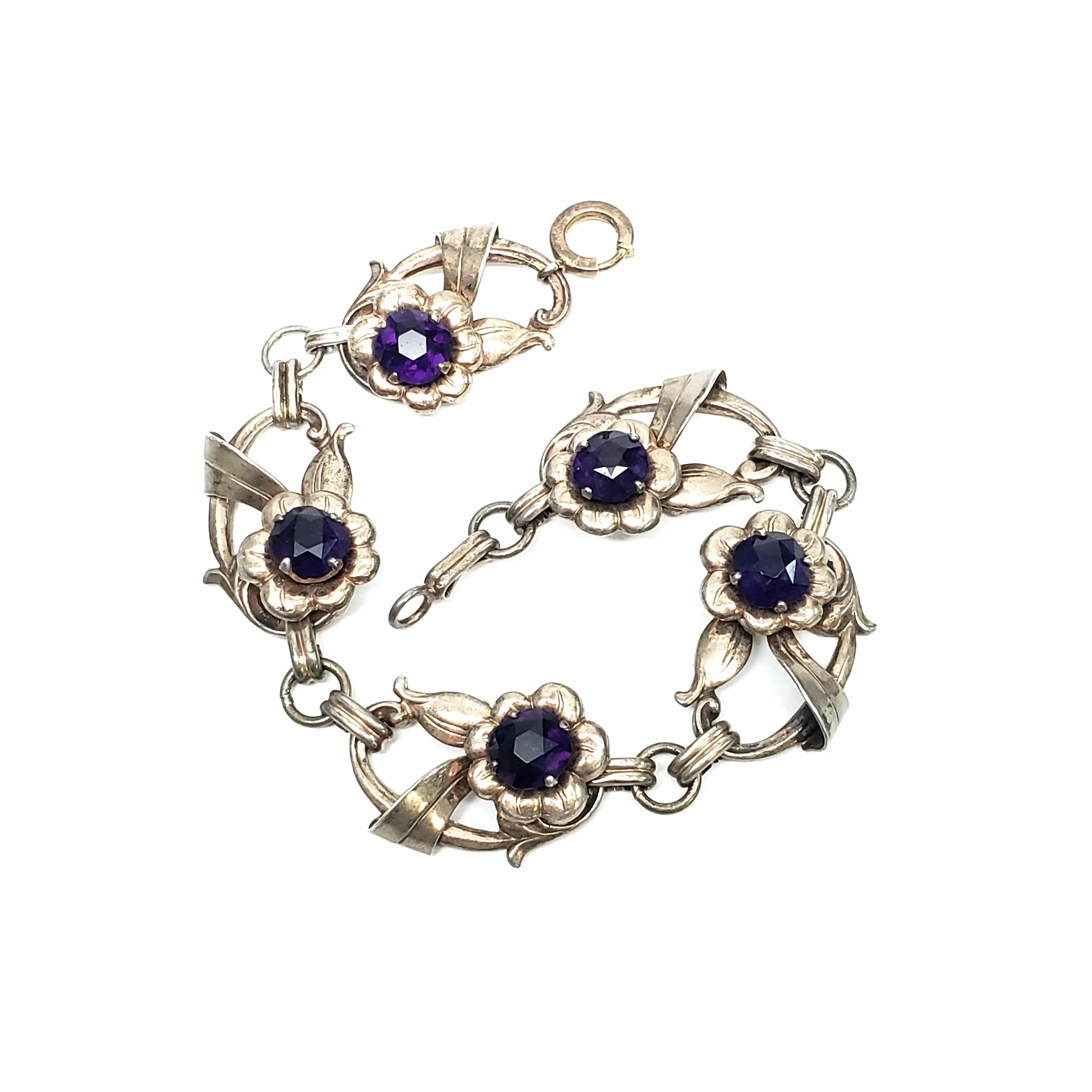 Gold vermeil over sterling silver link bracelet with purple glass stone by Harry Iskin.

Unique oval link bracelet with flower detail and purple glass stones.

Measures approx 8