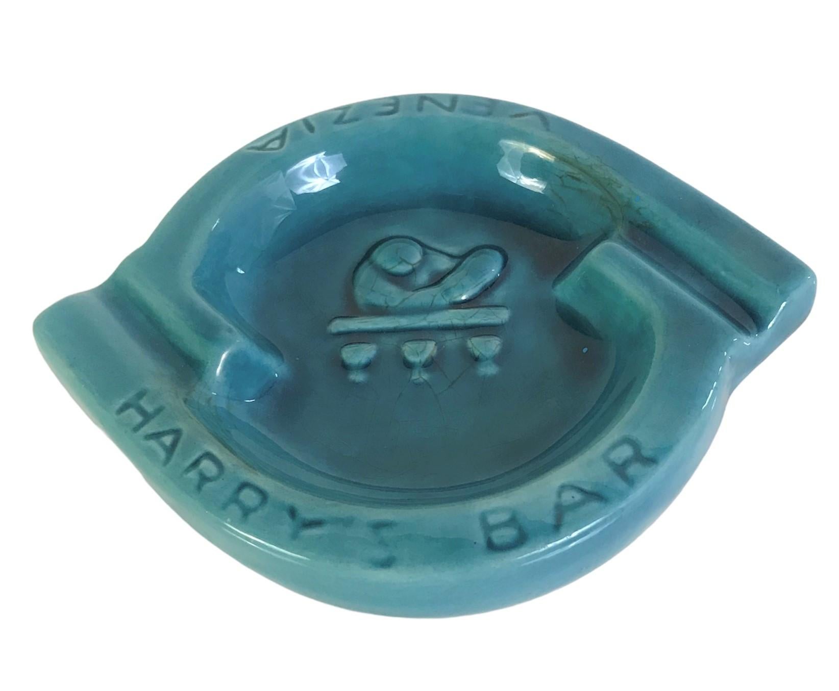 Fabulous Mid-Century Modern Ceramic Ashtray from the world-famous Harry’s Bar, Venice.  Turquoise blue ceramic with the signature bartender design mixing cocktails in relief.  HARRY’s BAR and VENEZIA incised and Dual cigarette / cigar rests. Clearly