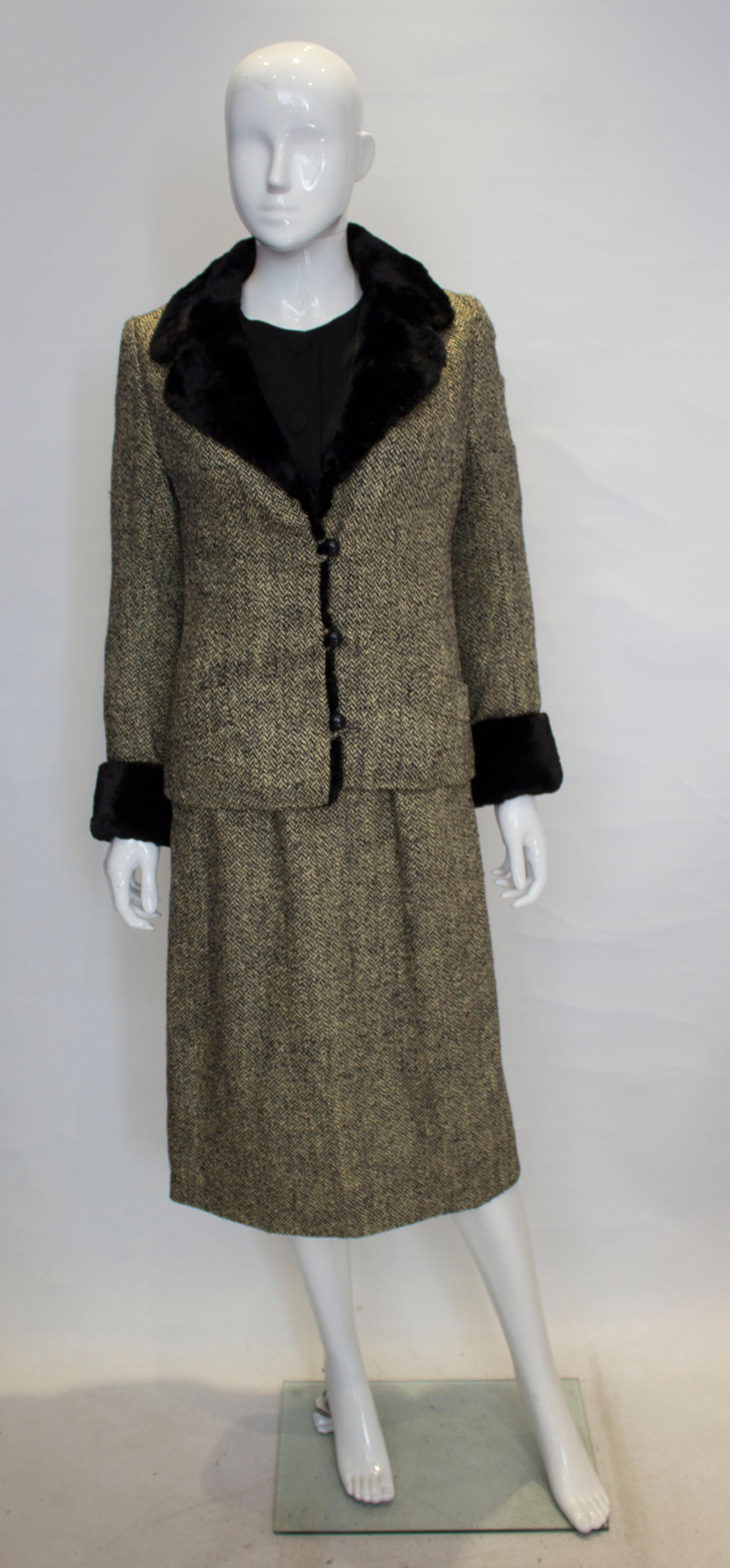 A chic dress and jacket by Hartnell. The dress has a black crepe like bodice with the lower area in a silk like tweed. The dress has four decorative buttons on the front, two pockets at the front, long sleeves with popper fastenings, a central back