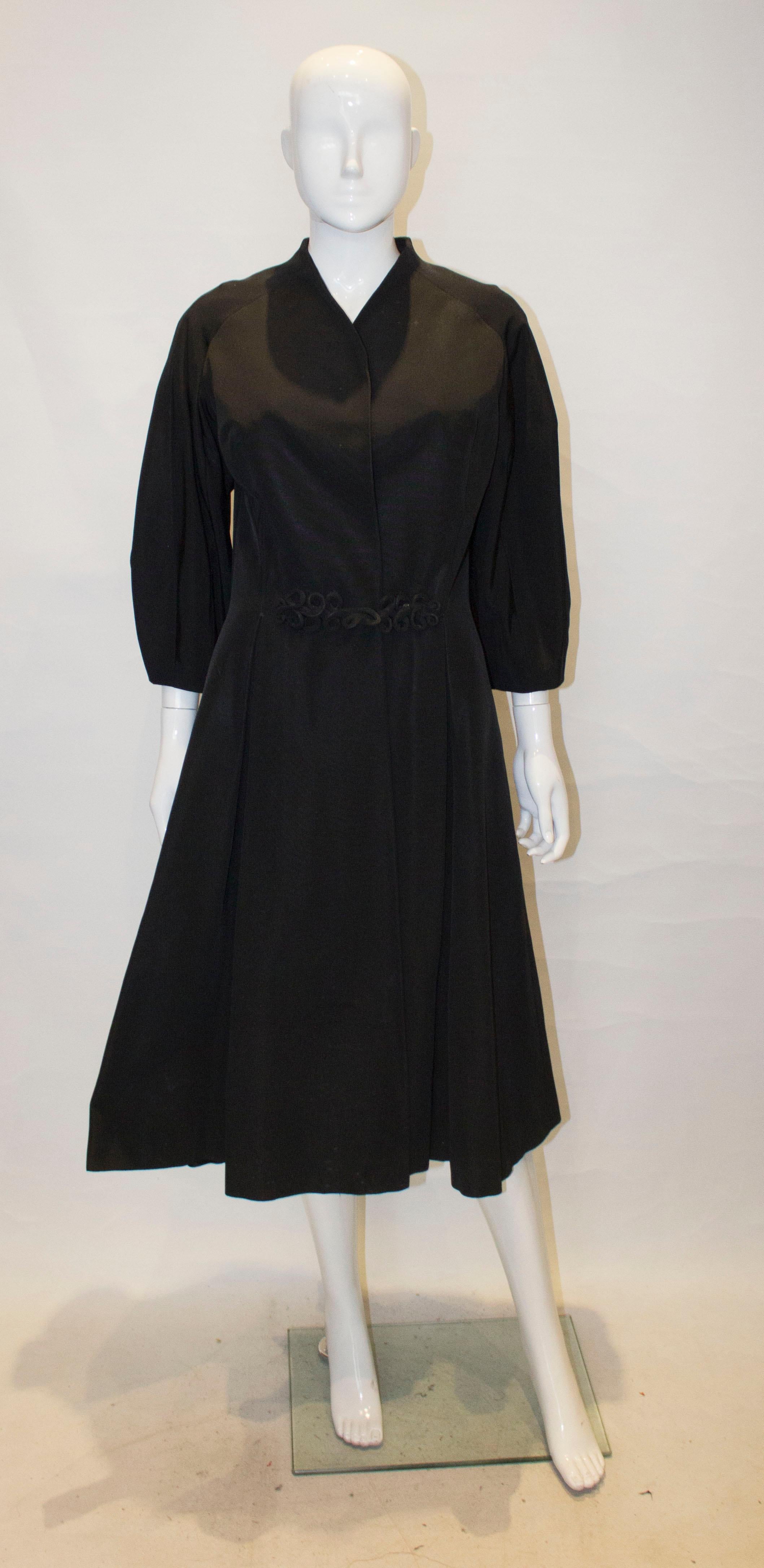 A wonderful vintage evening coat by Harvey Nichols. The coat is in a black grosgrain, and is collarless with a v neckline and pleats on the front and back. It is fully lined.