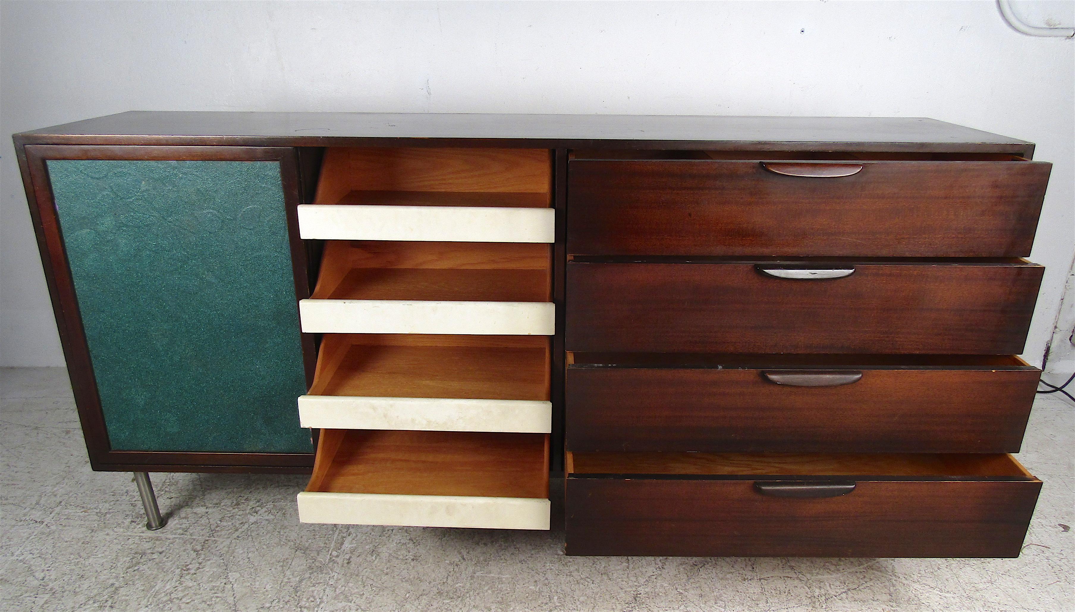 A stunning Mid-Century Modern sliding door credenza with a textured green front and four drawers. The sculpted pulls and dovetailed construction show quality craftsmanship at its best. Plenty of room for storage within its twelve hefty drawers.