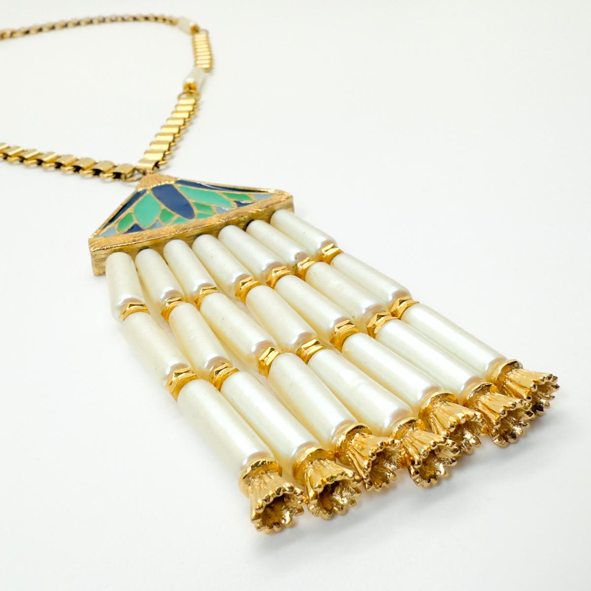 Un collier égyptien vintage de Hattie Carnegie. Une chaîne en forme de livre, décorée de perles allongées, mène à un pendentif spectaculaire de style néo-égyptien. Le pendentif, qui associe l'or brillant, l'émail et les perles avec leurs capuchons