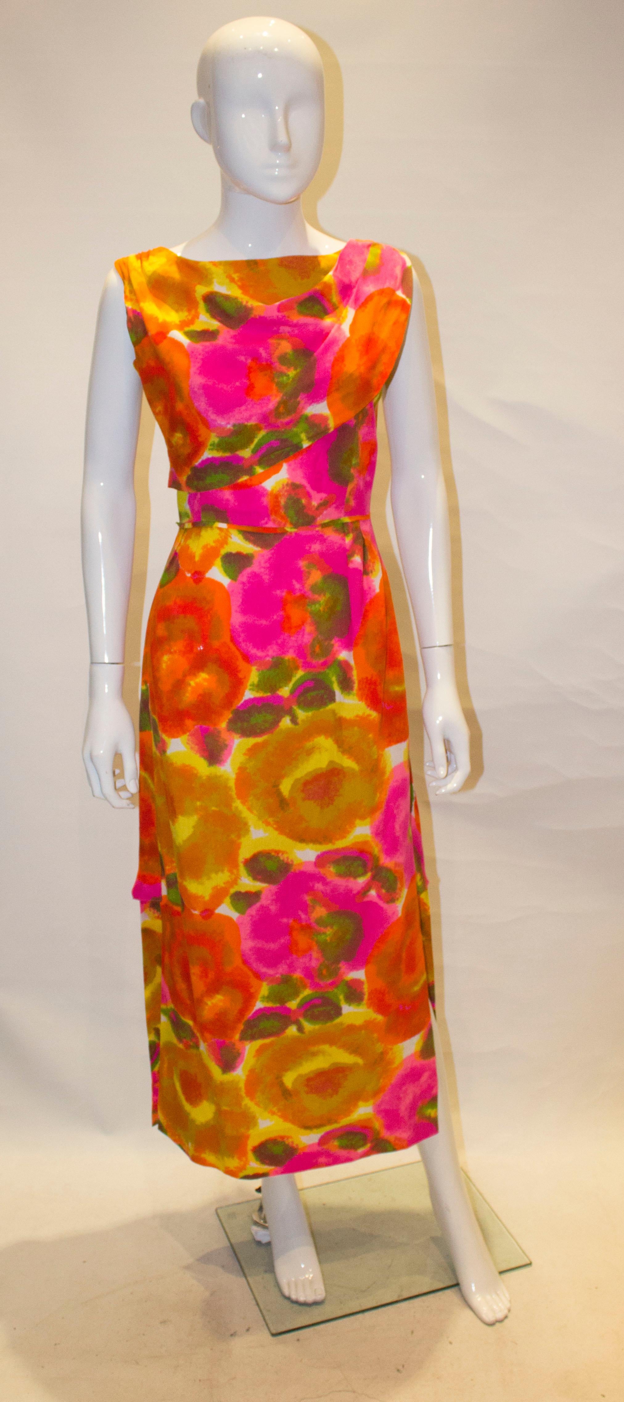 A wonderful vintage gown by Kahan of Honolulu. The dress is a vibrant mix of colours, pink, orange ,khaki, ivory and yellow. The dress has a drape at the front , with pleats on one shoulder and gathering on the other. It has a central back zip, and