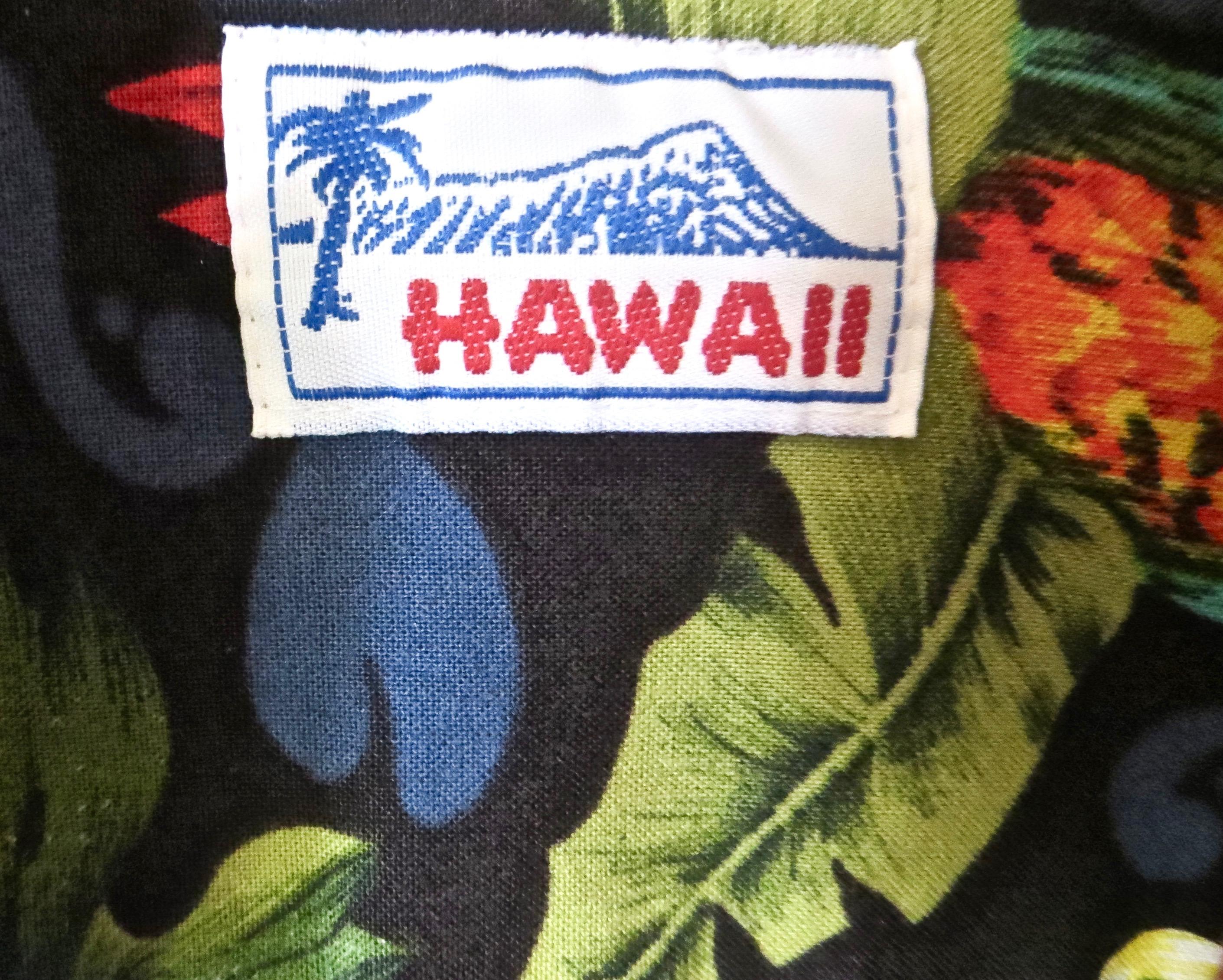 Cotton Hawaiian vintage shirt with flora and fauna theme of Hawaiian islands; including multiple parrots and abundant flowers in a multiplicity of crisp bright colors of blue, red, purple, green, and white; in 