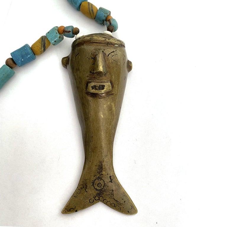 Vintage headhunter brass and trade bead necklace, Nagaland.

Trade beads with a brass medallion of a hunter's head shaped like a fish as the centerpiece, attributed to the Konyak and contiguous tribal groups. These types of brass heads are fashioned