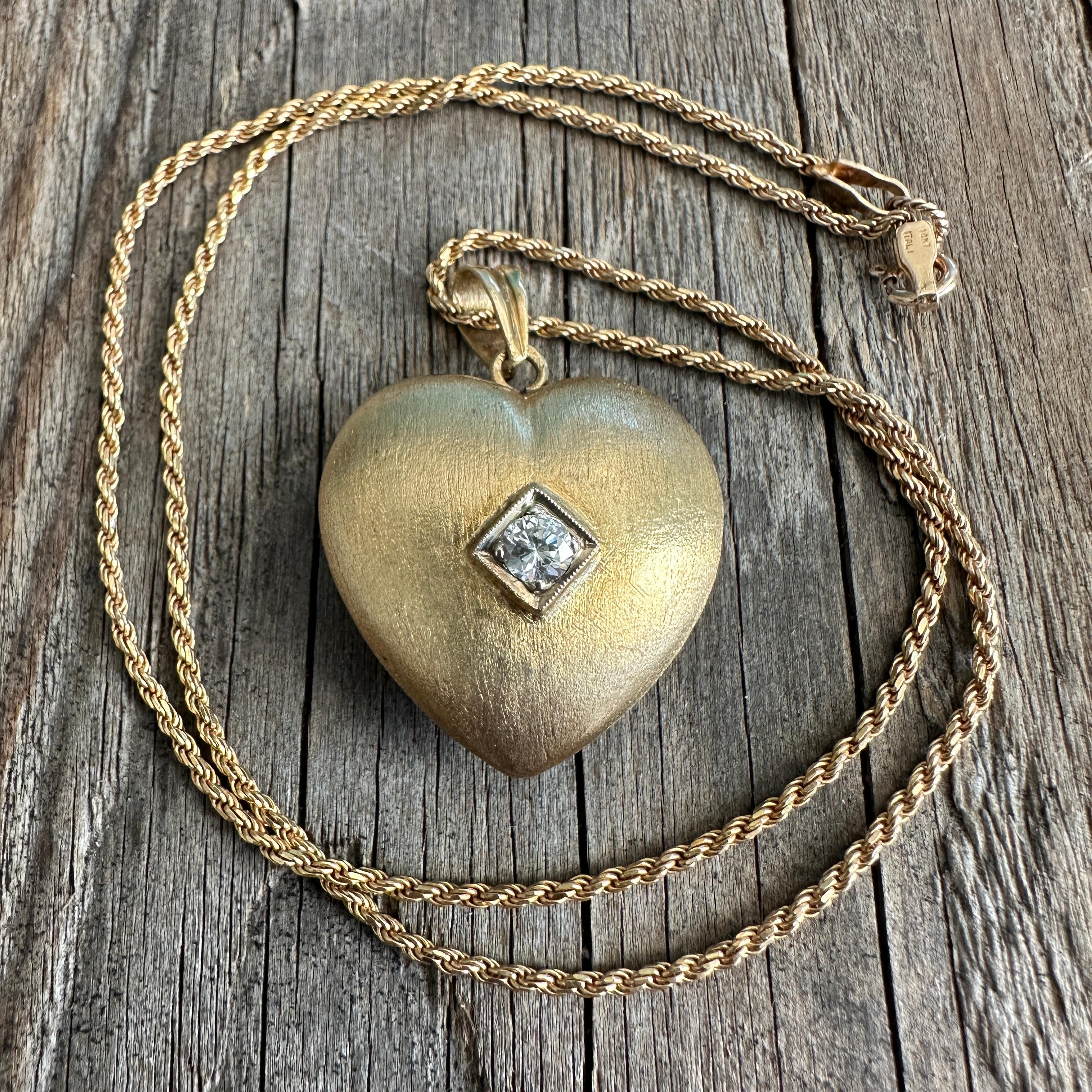 Details:
Super sweet vintage 14K diamond puffy heart pendant necklace! The puffy heart is textured in a silk pattern. The diamond measures 3.2mm, and is roughly .12 carats. The pendant hangs on a 16 inch, 14K gold rope chain hallmarked Italy. Please