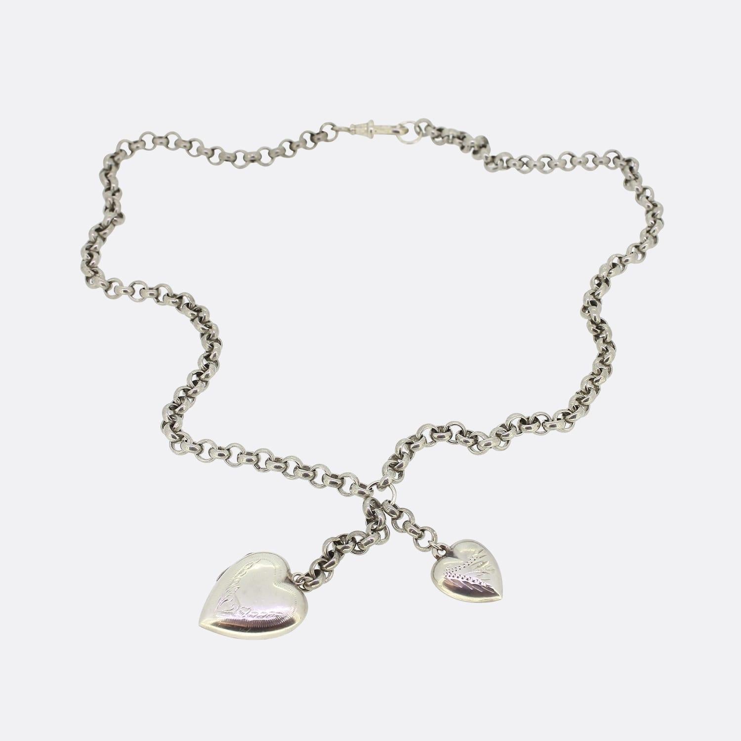 This is a vintage sterling silver belcher charm necklace. The necklace has two charms attached throughout the chain including a puffy engraved silver heart and an engraved silver heart locket. The whole chain and charms have been made in sterling