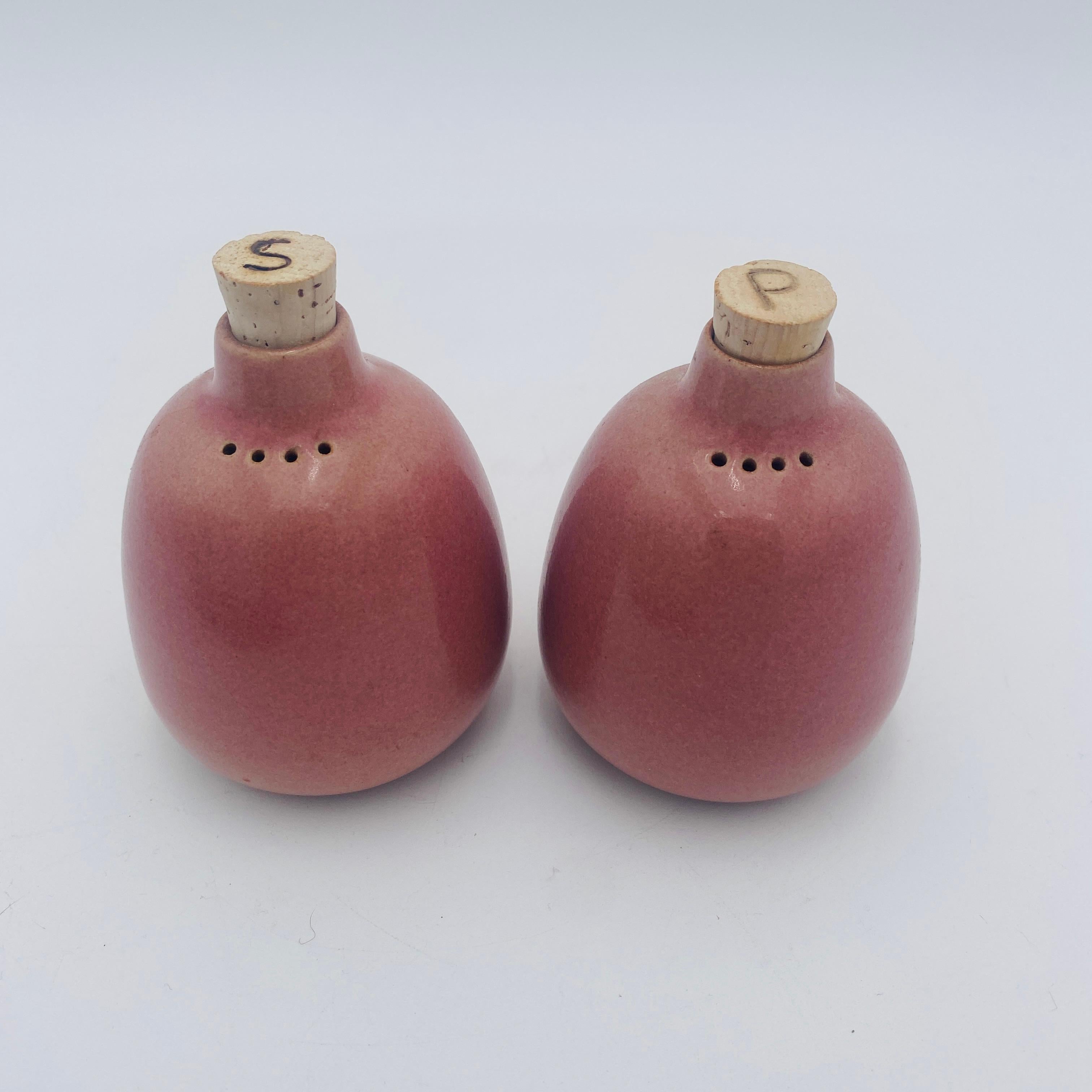 Ce rare ensemble de salières et poivrières émaillées de couleur rose par Heath Ceramics de Sausalito, CA, est parfait pour votre décor minimaliste du milieu du siècle. Les Shakers mesurent 4 pieds de haut par 3 pouces de large. Les fonds des deux