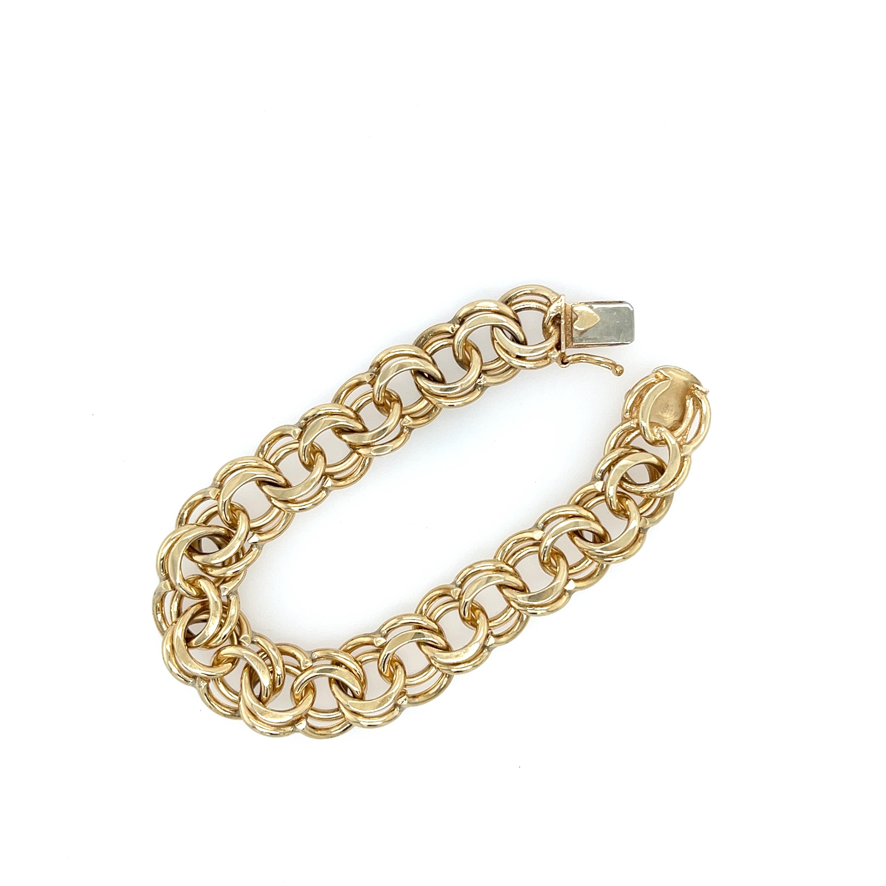 A vintage heavy double link charm bracelet with substantial weight! Crafted of 14K yellow gold, this bracelet is stamped with 
