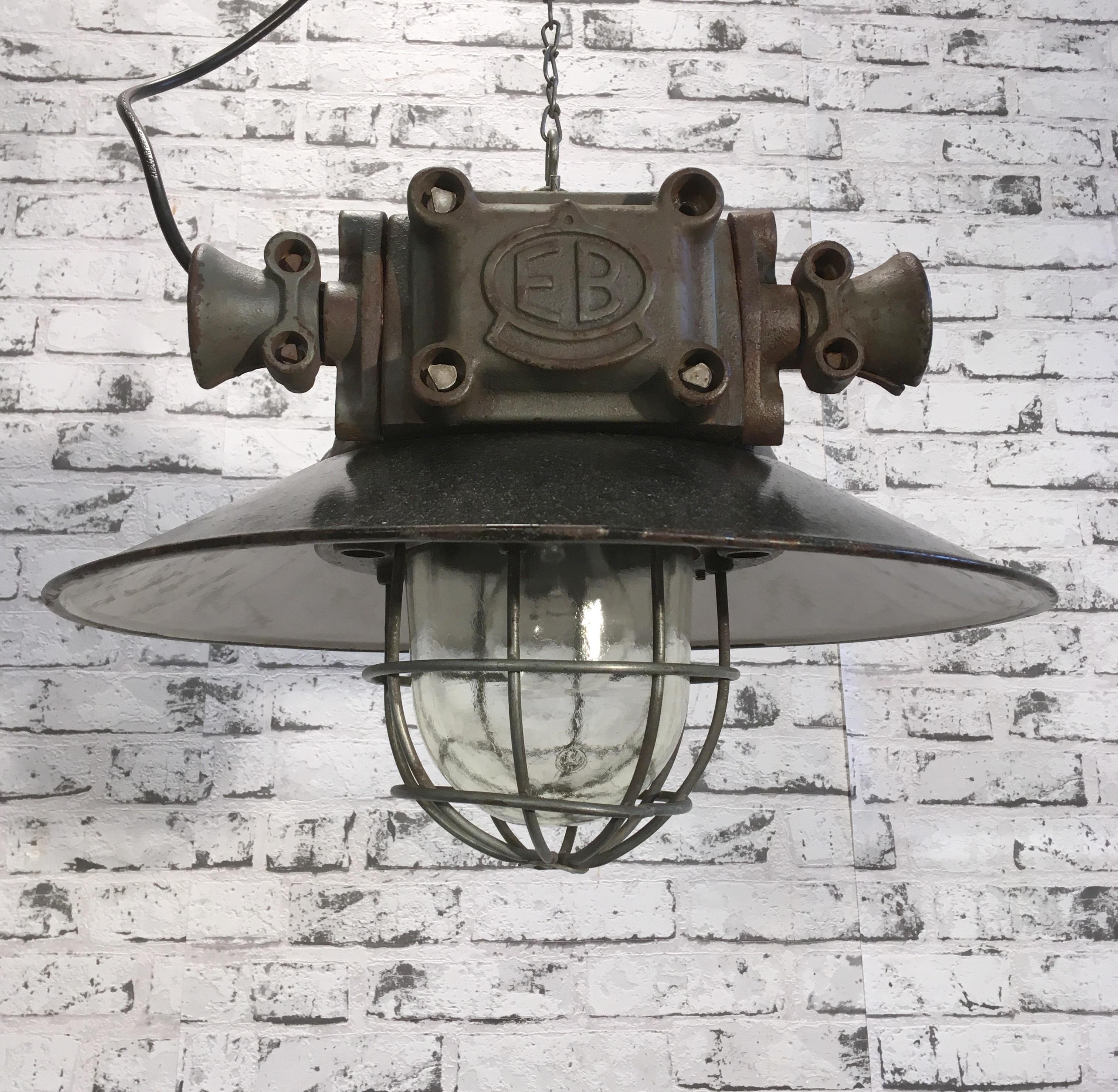This heavy explosion-proof lamp with enamel shade was made during the 1960s.These lamps were used in laboratories and Industrial plants, especially in areas of danger of explosion. It features cast iron body, enamel lampshade, iron grid and clear