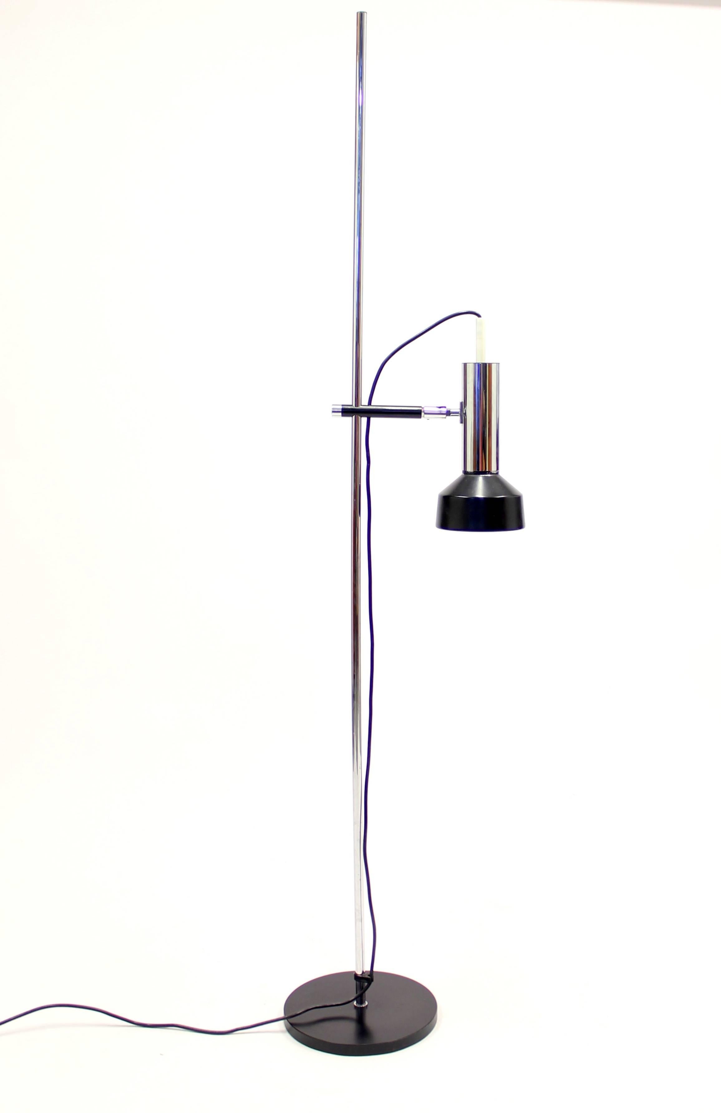 Vintage modernist height-adjustable chrome-plated floor light from the 1970s features a black shade and foot. The lamp can tilt and turn in all directions and may also be used as an up-light.