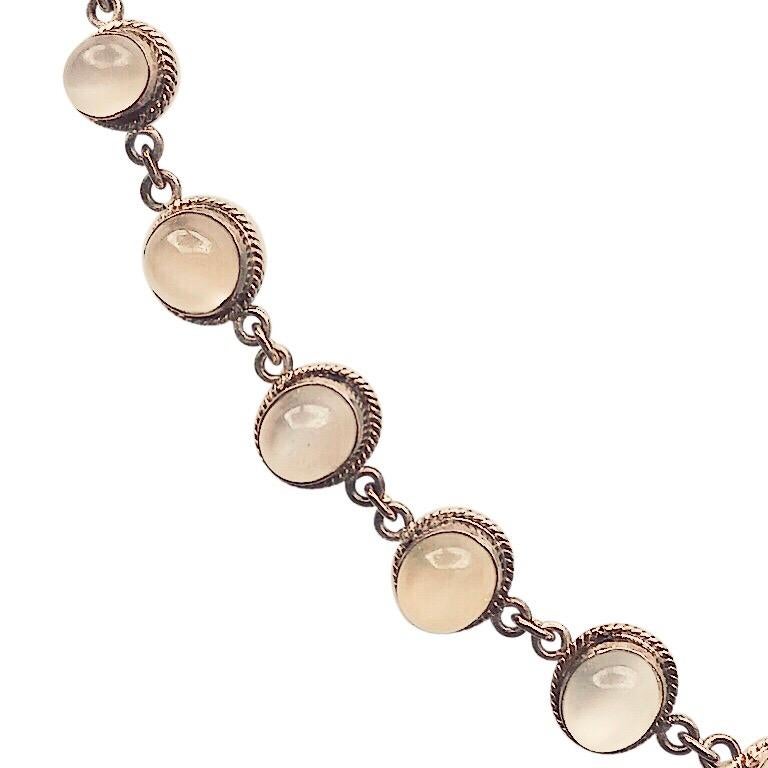 This moonstone bracelet is vintage heirloom early 20th century. It has ten moonstones with a variety of delicate, iridescent, pastel hues. Each stone is set in sterling with a braided bezel support. It has a sterling tube clasp which makes it easy