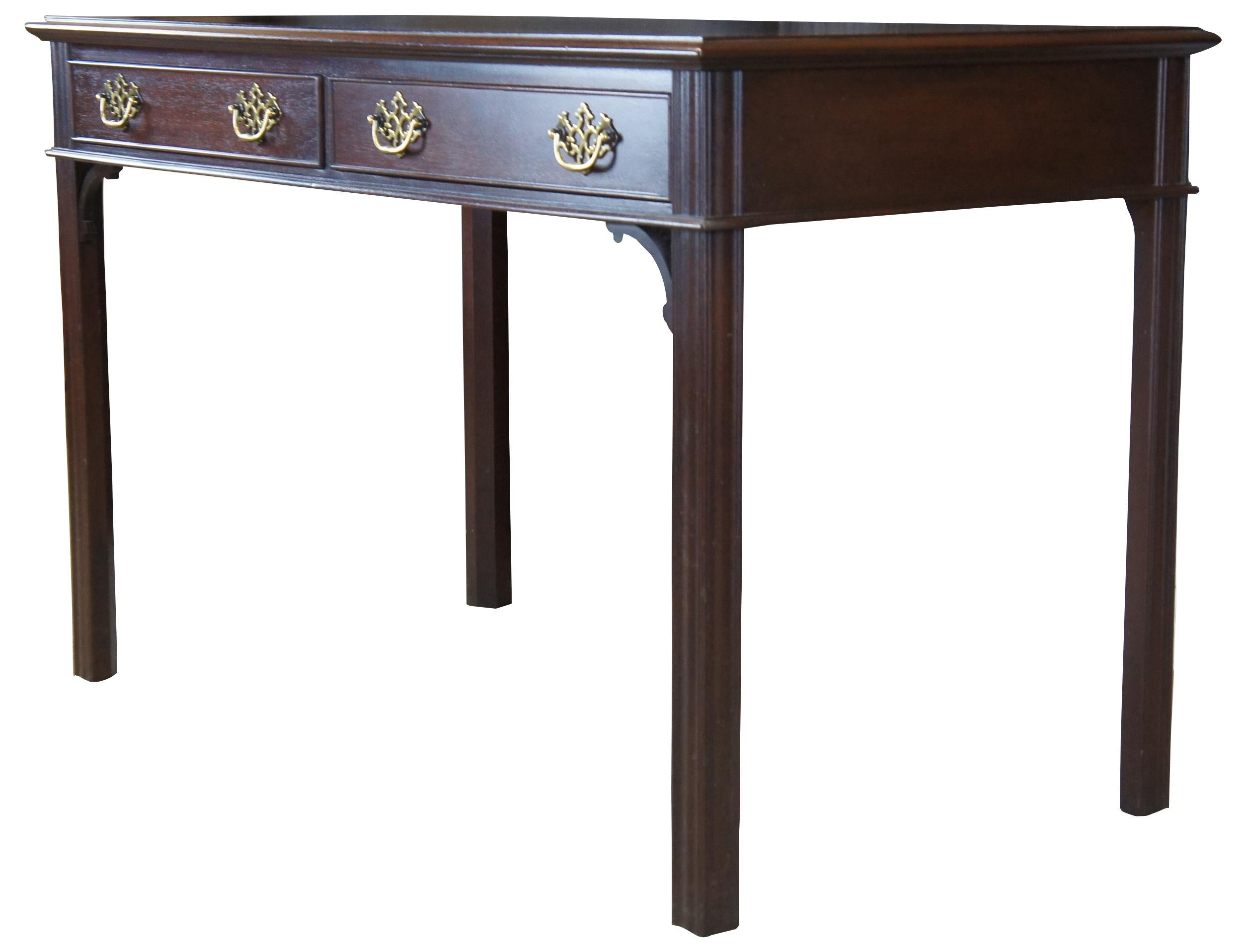 Vintage Hekman writing desk. Made of mahogany featuring rectangular form with tooled leather top, two drawers with brass hardware, and square form legs with a fluted edges.
 