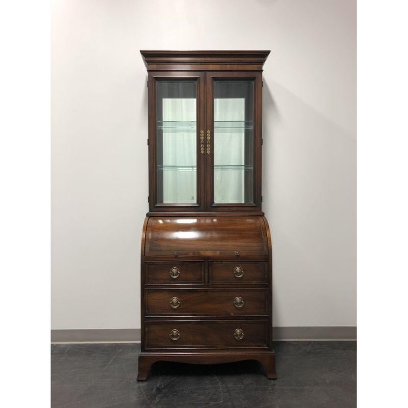 A Traditional style petite secretary desk by Hekman. Solid mahogany with brass hardware, crown moulding at top and bracket feet. Upper cabinet is lighted with mirrored back and two adjustable glass shelves behind beveled glass doors. Lower base