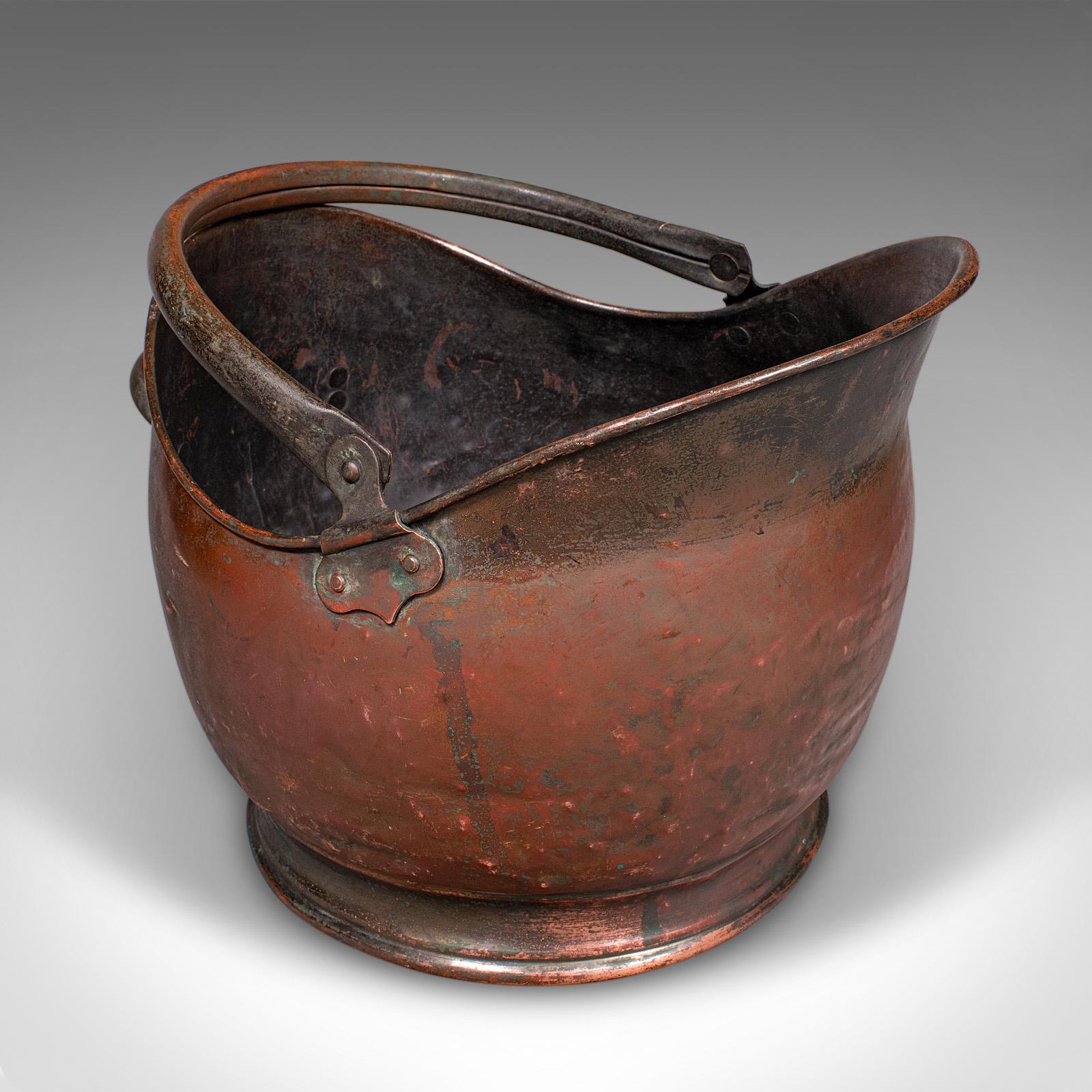 This is a vintage coal scuttle. An English, copper helmet fuel basket in Victorian revival taste, dating to the mid 20th century, circa 1950. A classically styled piece, it brings a touch of Victorian fireplace charm to any home.

Crafted in the