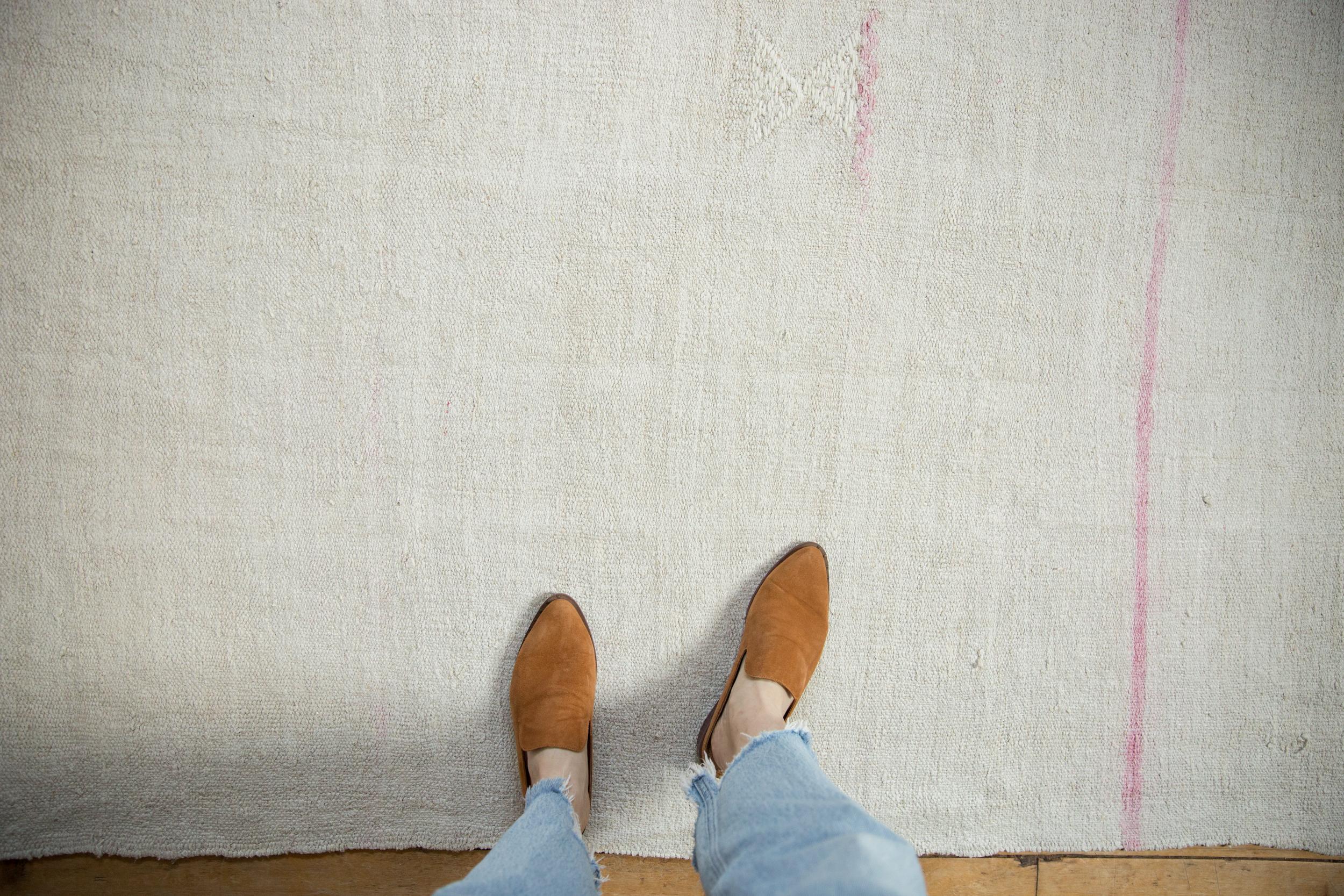 :: Kilim a trama semplice con strisce orizzontali in tonalità tenui e un piccolo elemento cucito a forma di lente d'ora o di montagna che accentua la parte centrale. I colori e le sfumature includono: Platino, argento, beige, avorio, rosa e altri