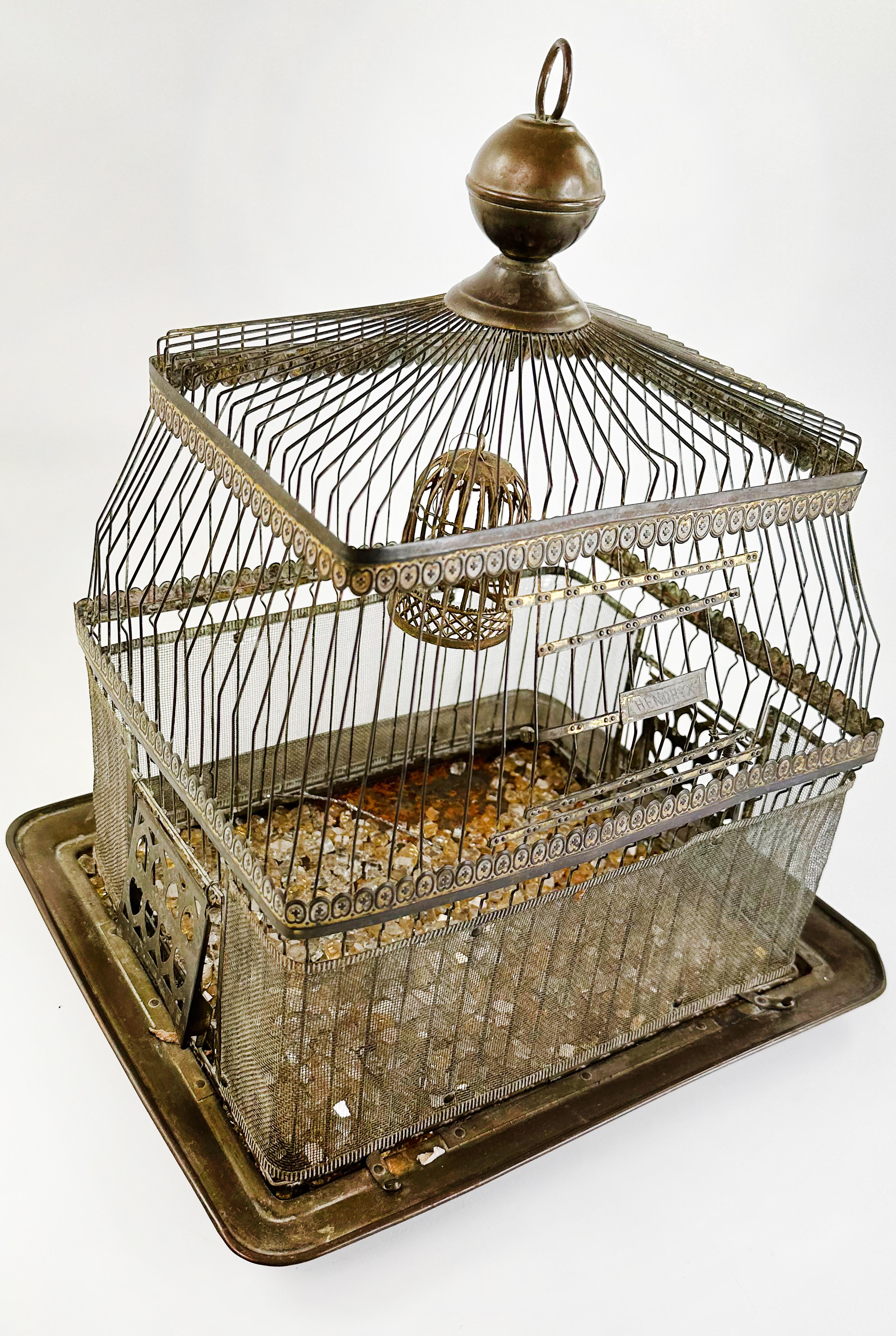 An elegantly crafted and charming vintage birdcage. Made with brass and steel wire. 

The top of this piece has an intricately cut light green leaf design. The bottom is adorned with small chunks of glass. A miniature bird cage stands in the top
