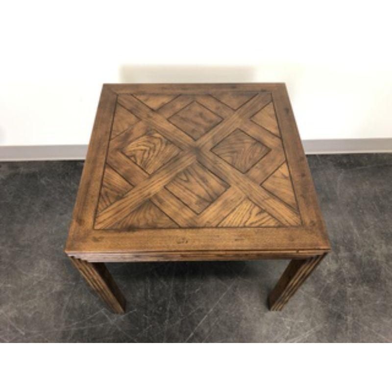 A Campaign style square accent table by Henredon, from their Artefacts Collection. Solid oak with a slightly distressed finish, banded top with a parquetry pattern, ribbing to the apron, and ribbed square straight legs. Made in Morganton, North