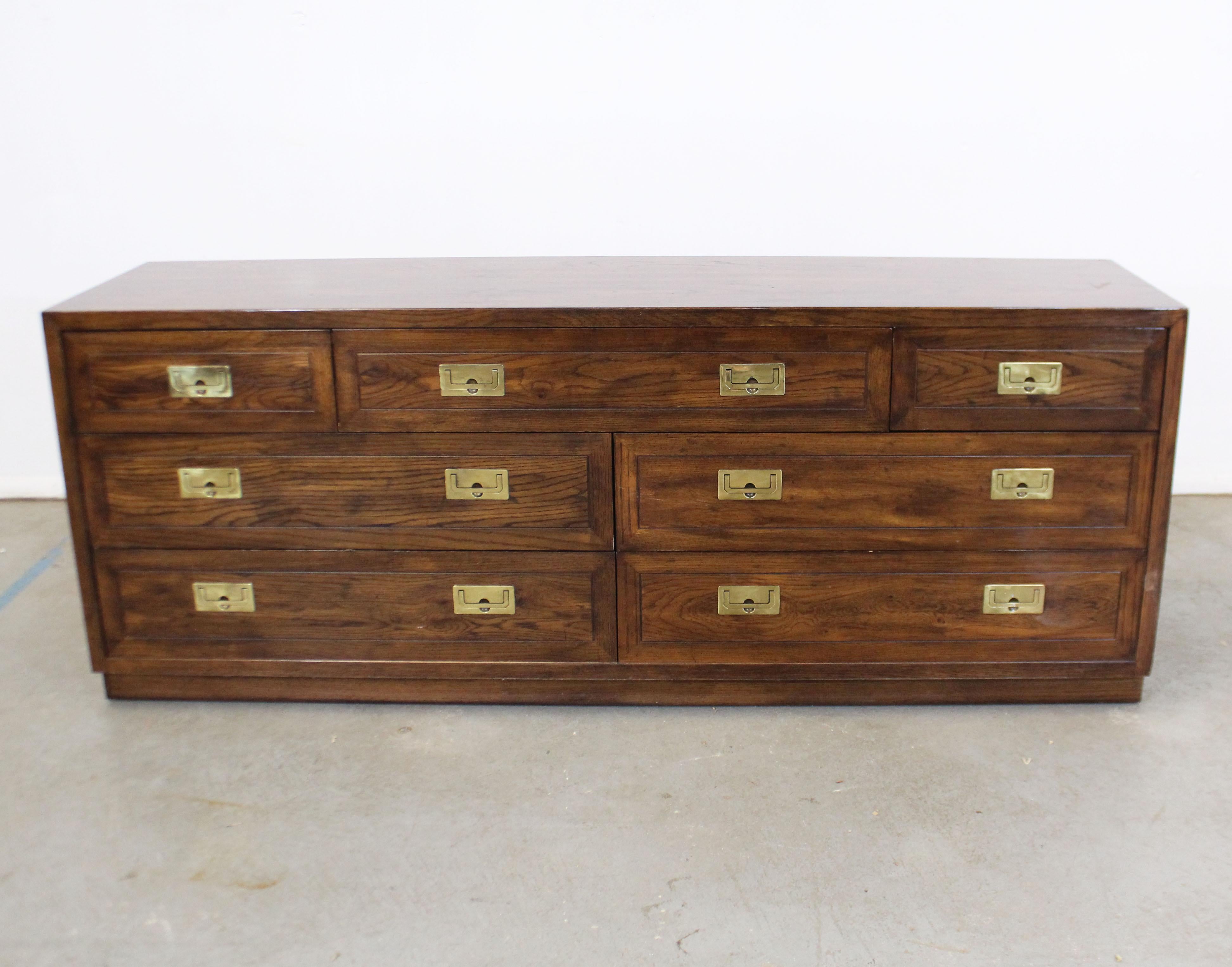 Offered is a vintage Campaign oak dresser with brass accents made by Henredon. This is a solid dresser with nine dovetailed drawers. Three drawers have removable dividers. It is in good condition, with some age wear including edge wear, scratches,