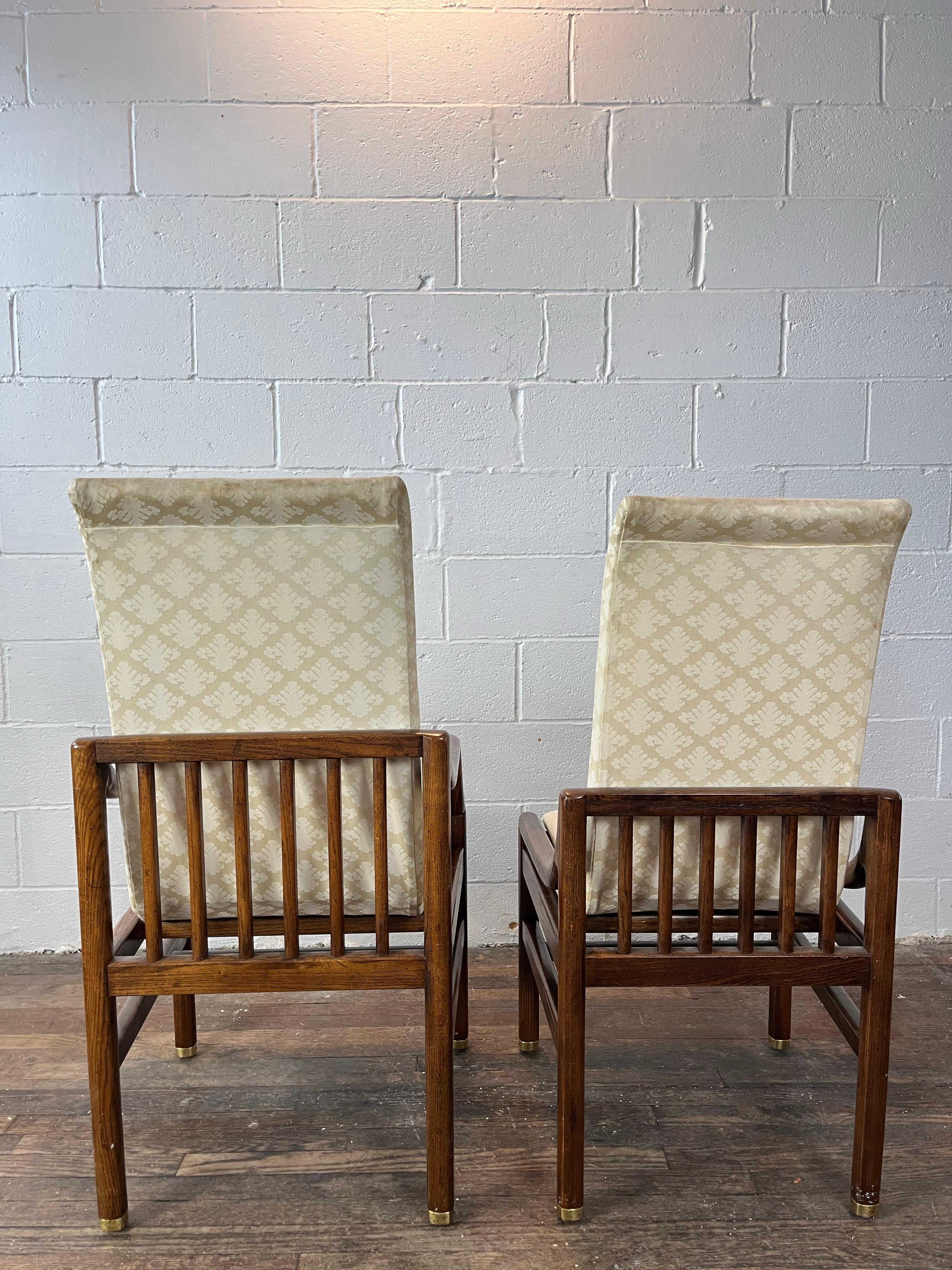 Mid-Century Modern sculptural dining chairs by Henredon. Consisting of two armchairs and six side chairs. Chairs feature classic floating frames with brass feet caps and covered in white cream upholstery. They are well made and sturdy. All branded