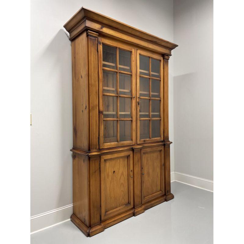 A Chippendale style china cabinet by Henredon, for Polo Ralph Lauren. Distressed pine with brass hardware, crown molding to top, fluted columns to sides and lower center. Upper cabinet features lockable dual paned wavy glass doors with three