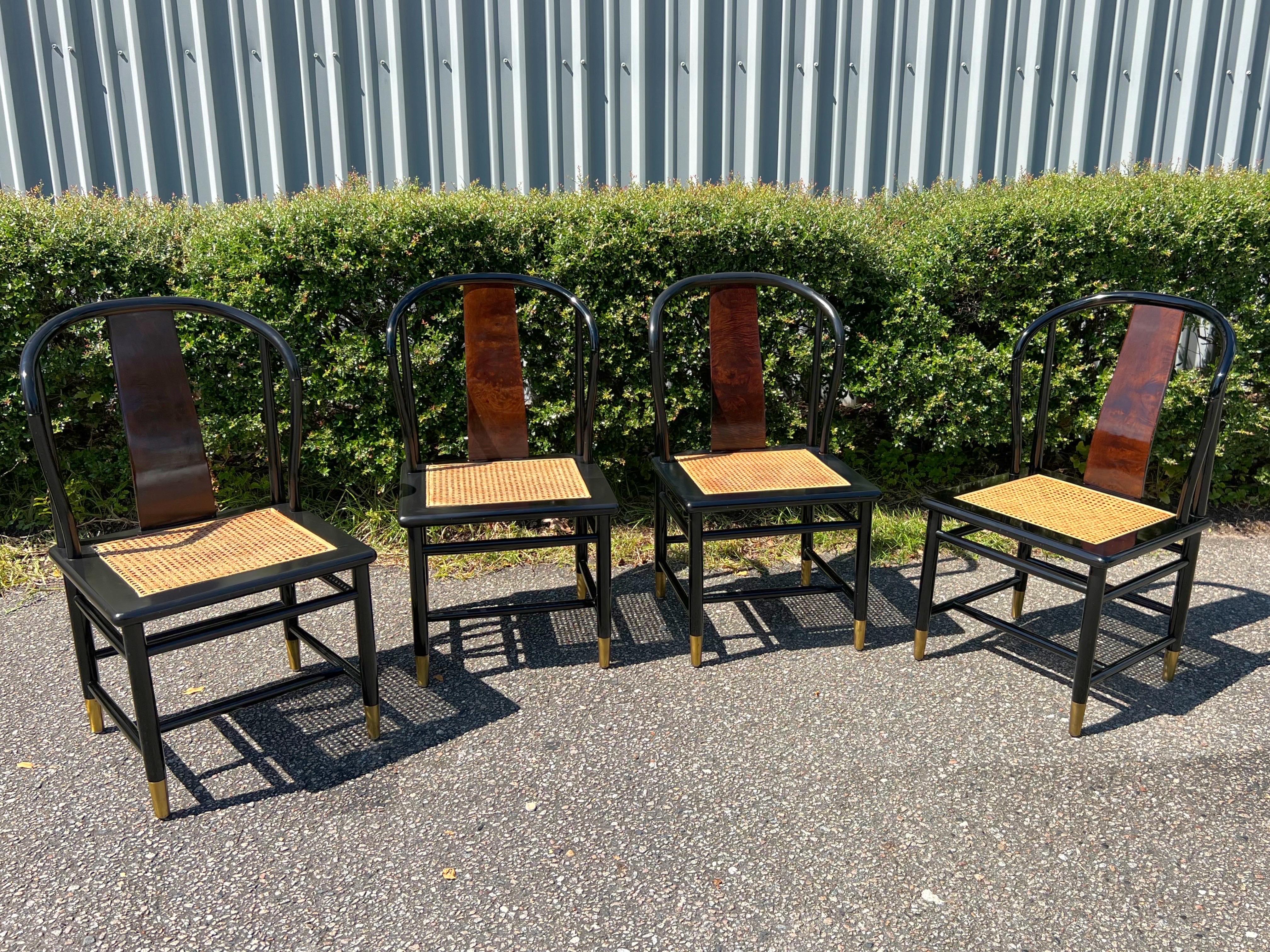 The chairs (four in total) feature a black lacquered, wooden frame with burl back splats, caned seats, and brass sabots. A luxurious set in very nice, vintage condition with only a few, light scuffs to the lacquer and light wear to the unpolished,