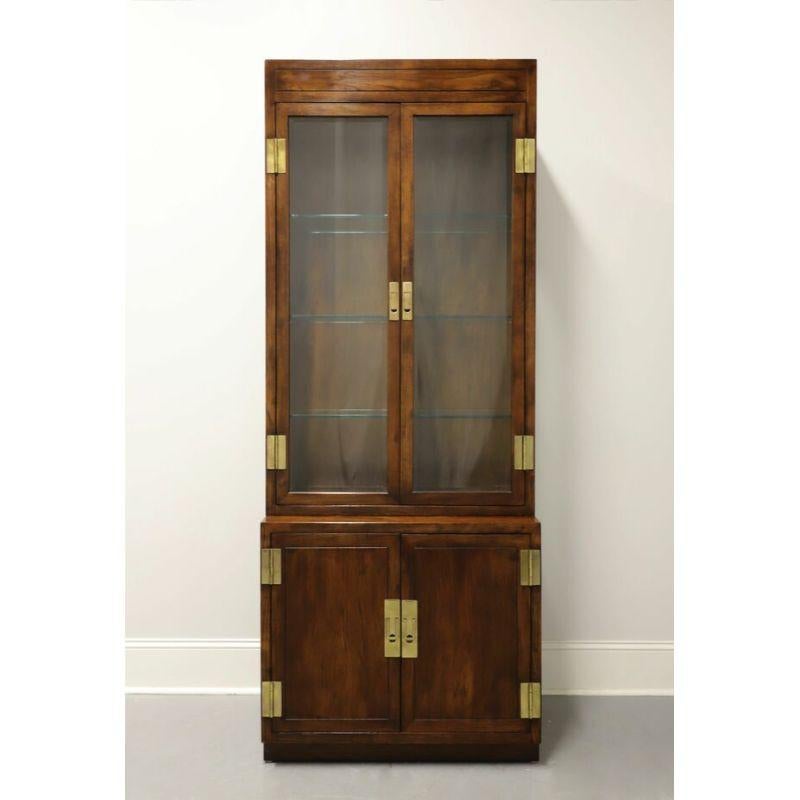 A Campaign style narrow display cabinet by Henredon, from their Scene One Collection. Fruitwood with brass hardware. Upper cabinet with dual beveled glass doors and side panels, lighted interior with dimmer switch and three adjustable plate grooved