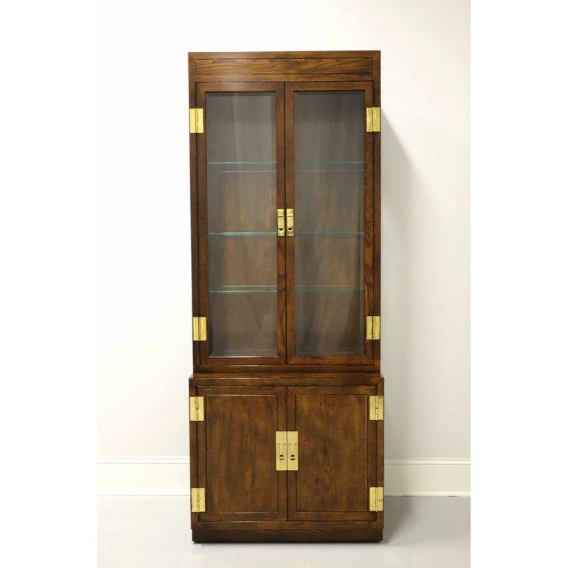 A Campaign style narrow display cabinet by Henredon, from their Scene One Collection. Fruitwood with brass hardware. Upper cabinet with dual beveled glass doors and side panels, lighted interior with dimmer switch and three adjustable plate grooved