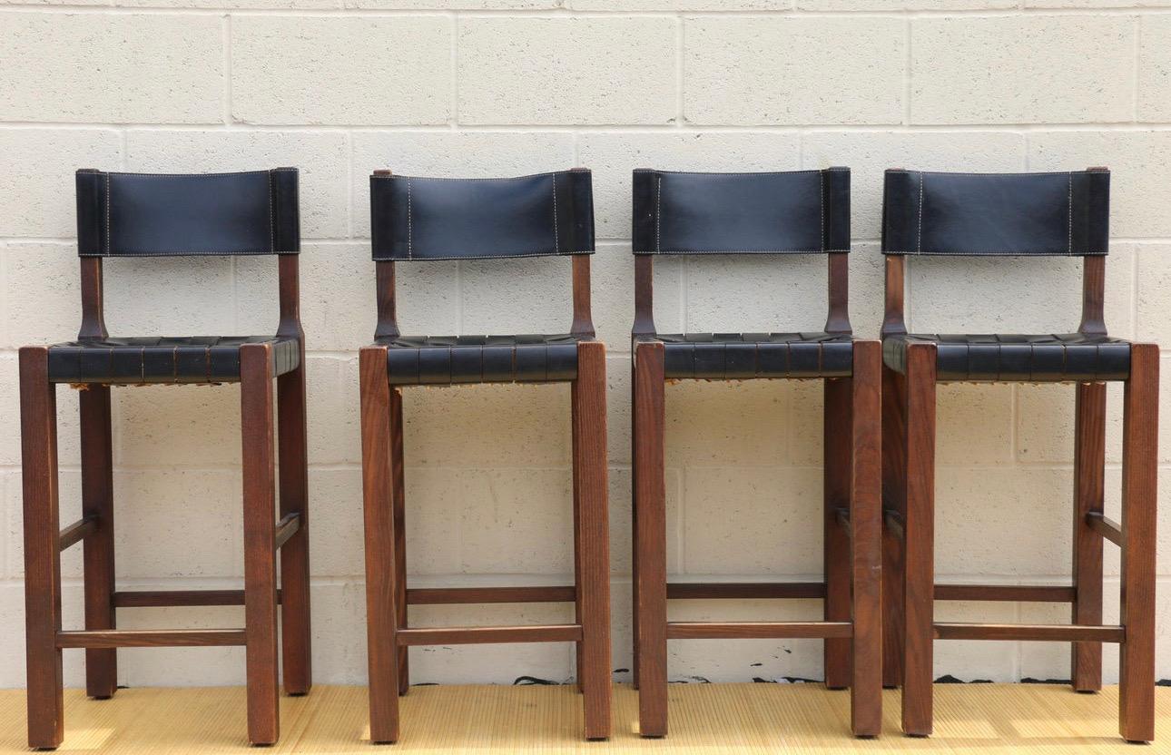 Iconic vintage set of four bar stools designed by Henry Benguelin. All of them have the logo in the back. They are made in Italy. Very good quality bar stool made of woven leather and wood. Braided leather straps seat detail. Two of them looks like
