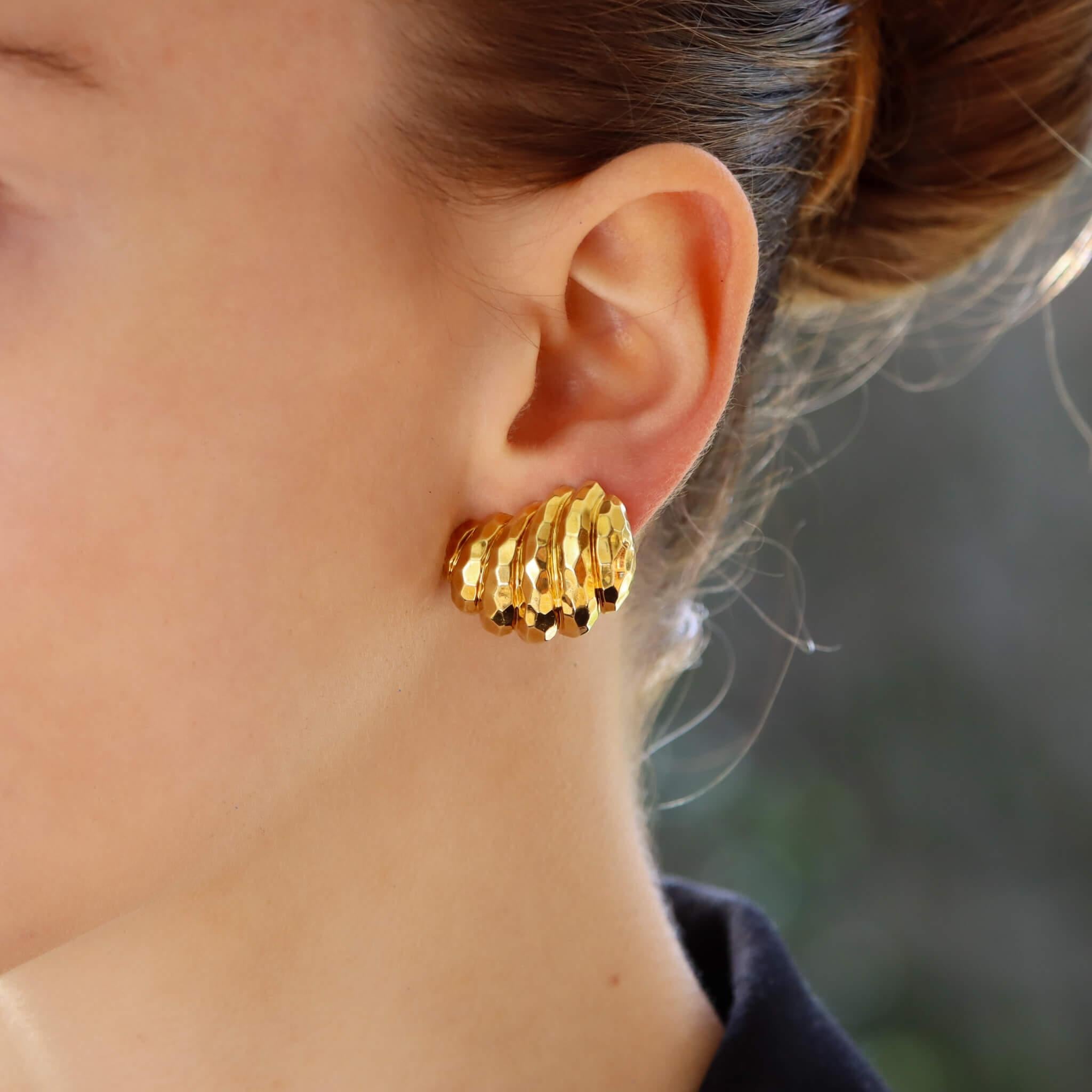 A unique vintage pair of Henry Dunay retro inspired hammered gold earrings set in 18k yellow gold.

Each earring is composed of a twirled shell-like motif which is completely decorated with a hammered gold effect. They are secured to reverse with a