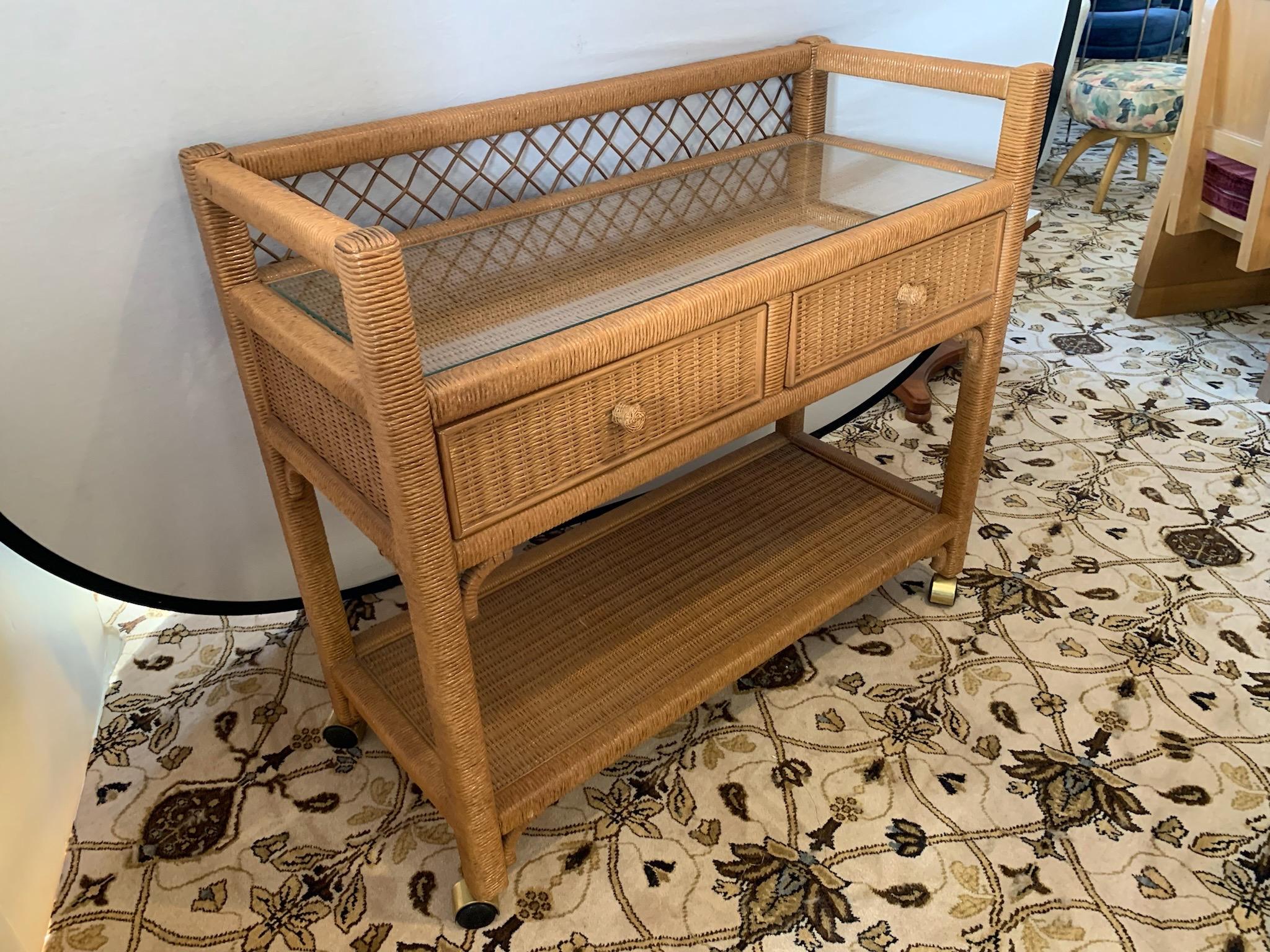 Vintage rattan wrapped bar/serving cart set on casters by Henry Link Furniture. Features double-tiered body and casters for added convenience. This vintage piece features the original “natural” color. Always ready to roll from happy hour to fancy