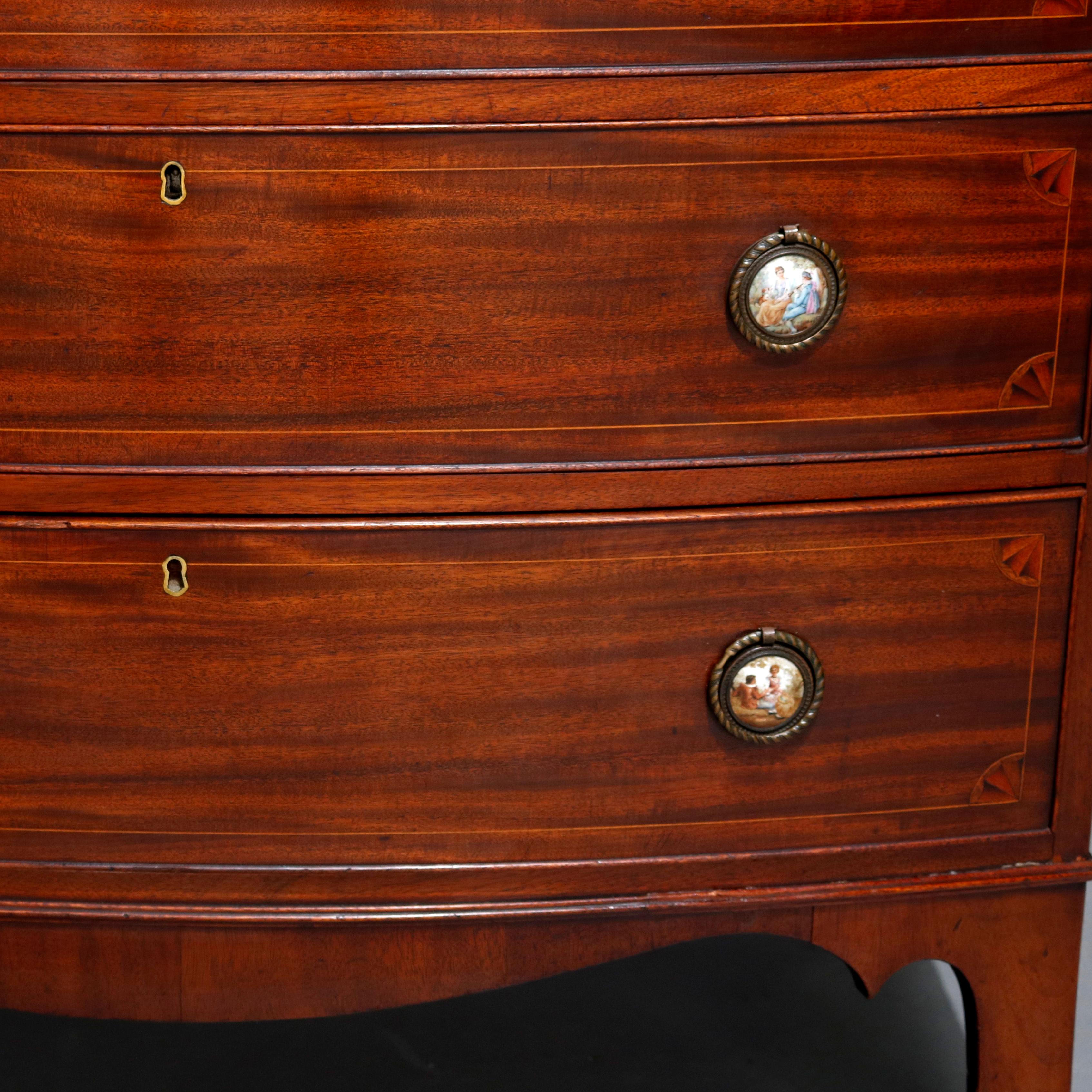 A vintage Hepplewhite style chest of drawers offers deeply striated mahogany construction in bow front form with four graduated long drawers each having inlaid satinwood banding and quarter fan corners with Sevres School hand painted porcelain