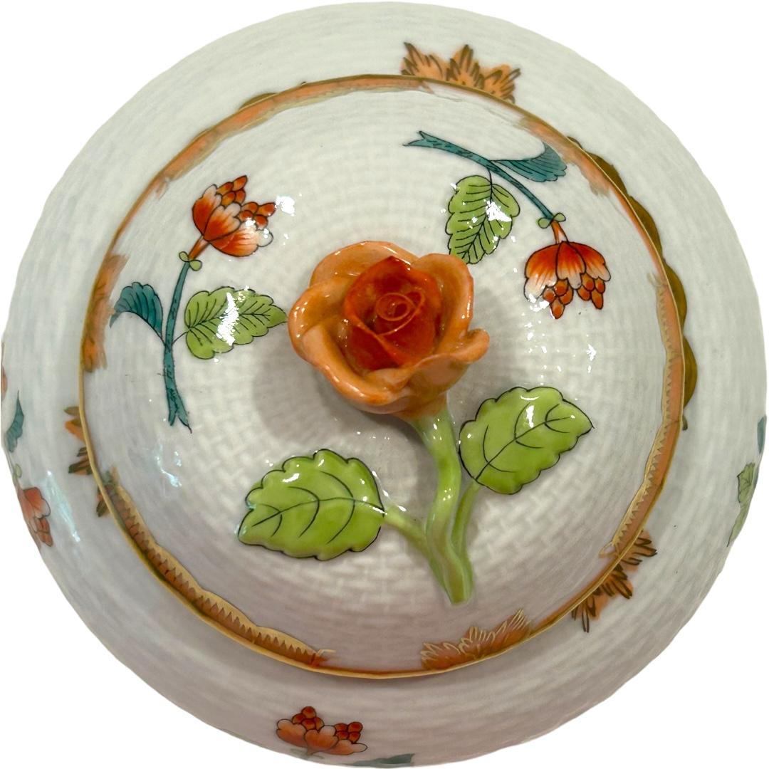 This vintage Herend decorative box/jar is a beautiful addition to your collection.  The box features a raised basket pattern with an eye-catching orange rose knob as the handle.  The jar is decorated in a floral motif accented in gold. Made in