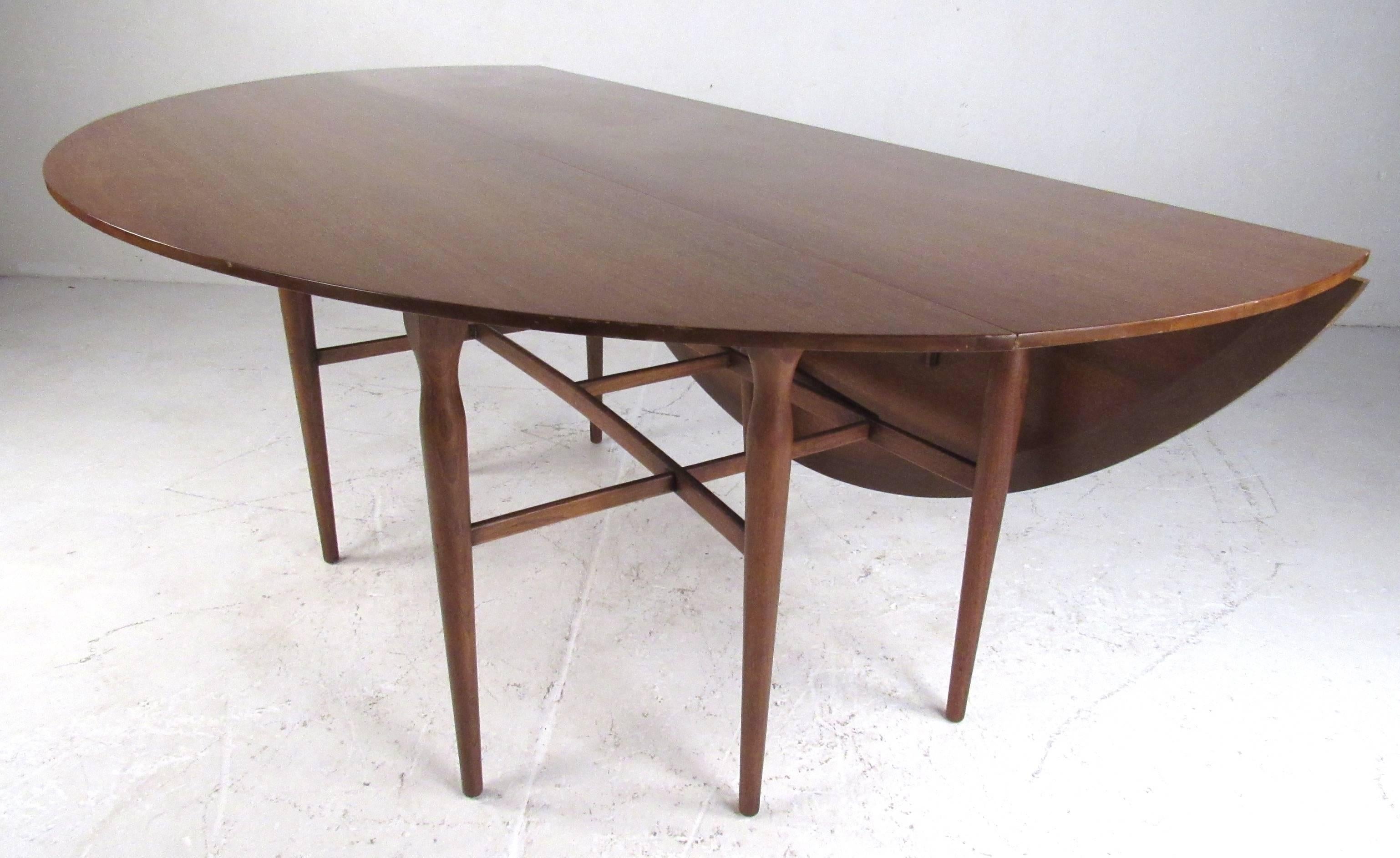Beautiful walnut gateleg dining table by Heritage-Henredon, circa 1960s. Featuring tapered legs and two folding leaves which expand the table from 19.5