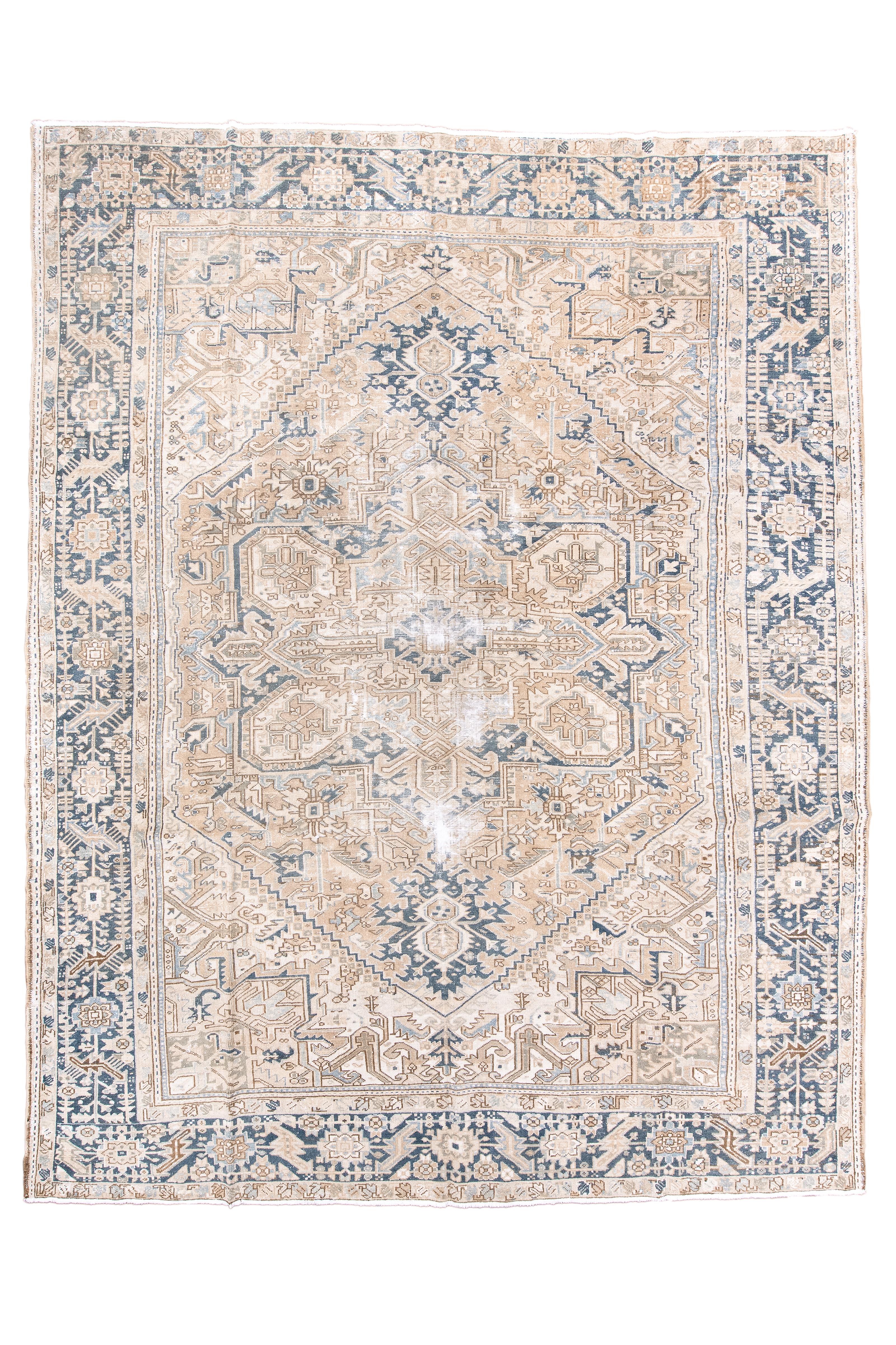 Aunque manchada, esta pieza de pueblo muestra un borde azul oscuro de estilo franja muy interesante, con rosetas y hojas dobladas, todo sobre una barra, con más hojas y otras formas mezcladas. La alfombra presenta un campo rosa claro con medallón