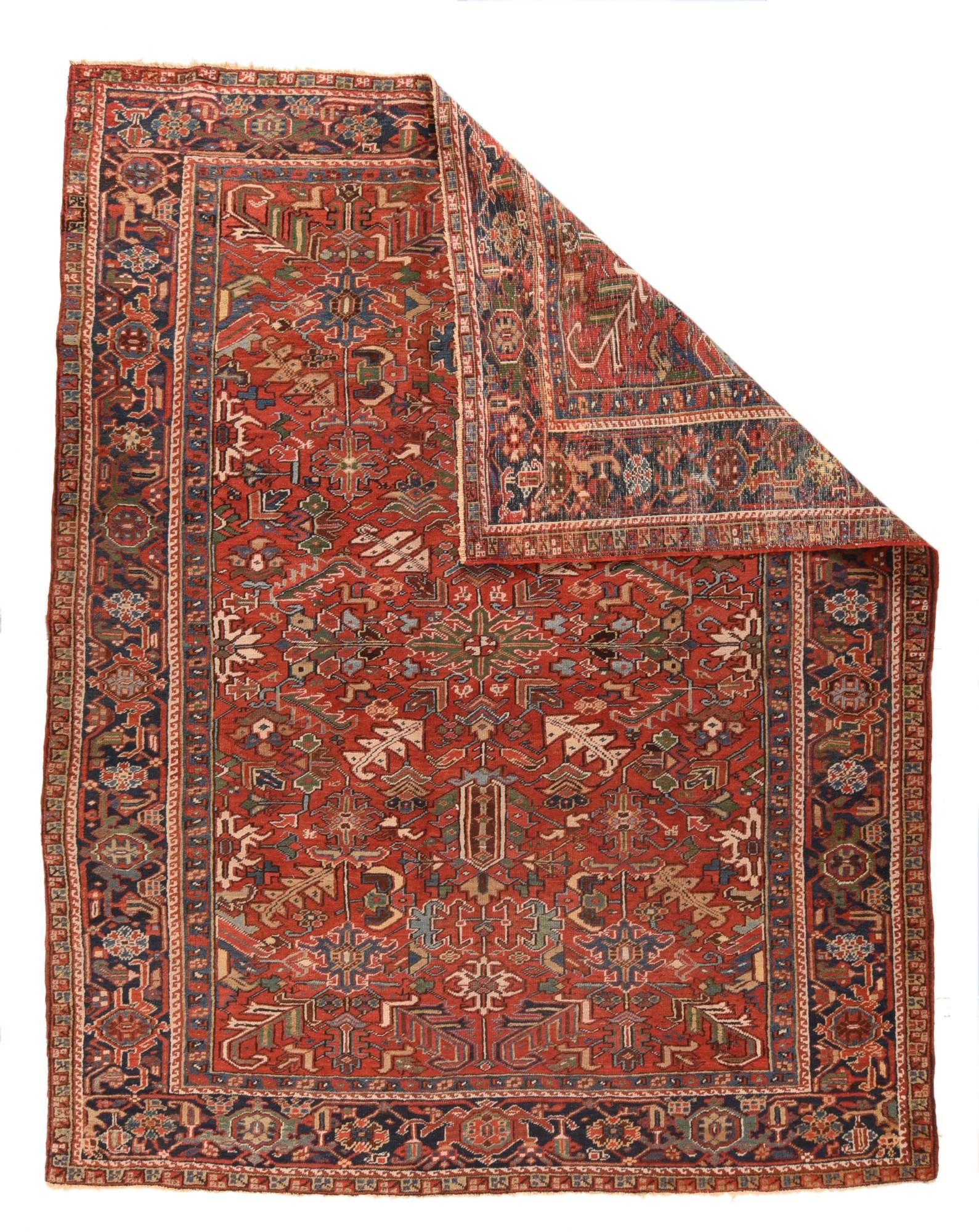 Vintage Heriz rug 7'4''x¬† 9'3''. This all-natural dye rustic NW Persian piece shows a red field with a characteristic pattern of sharply jagged leaves, hooked stiff leaves, and two ragged palmettes with tall hexagon centres, set around a central