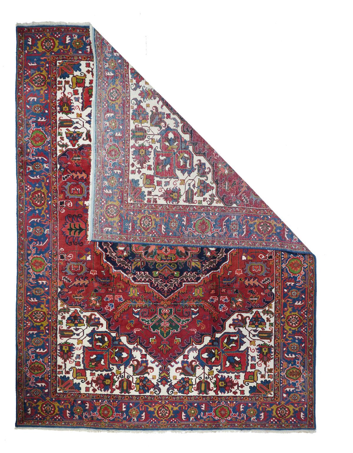 Vintage Heriz Rug 8'2'' x 11'. A stylistically individual NW Persian rural carpet with a geometrically scalloped navy medallion with a s pinched square burnt salmon centre, on a ketchup red field. Ivory corners with obliquely projecting palmettes