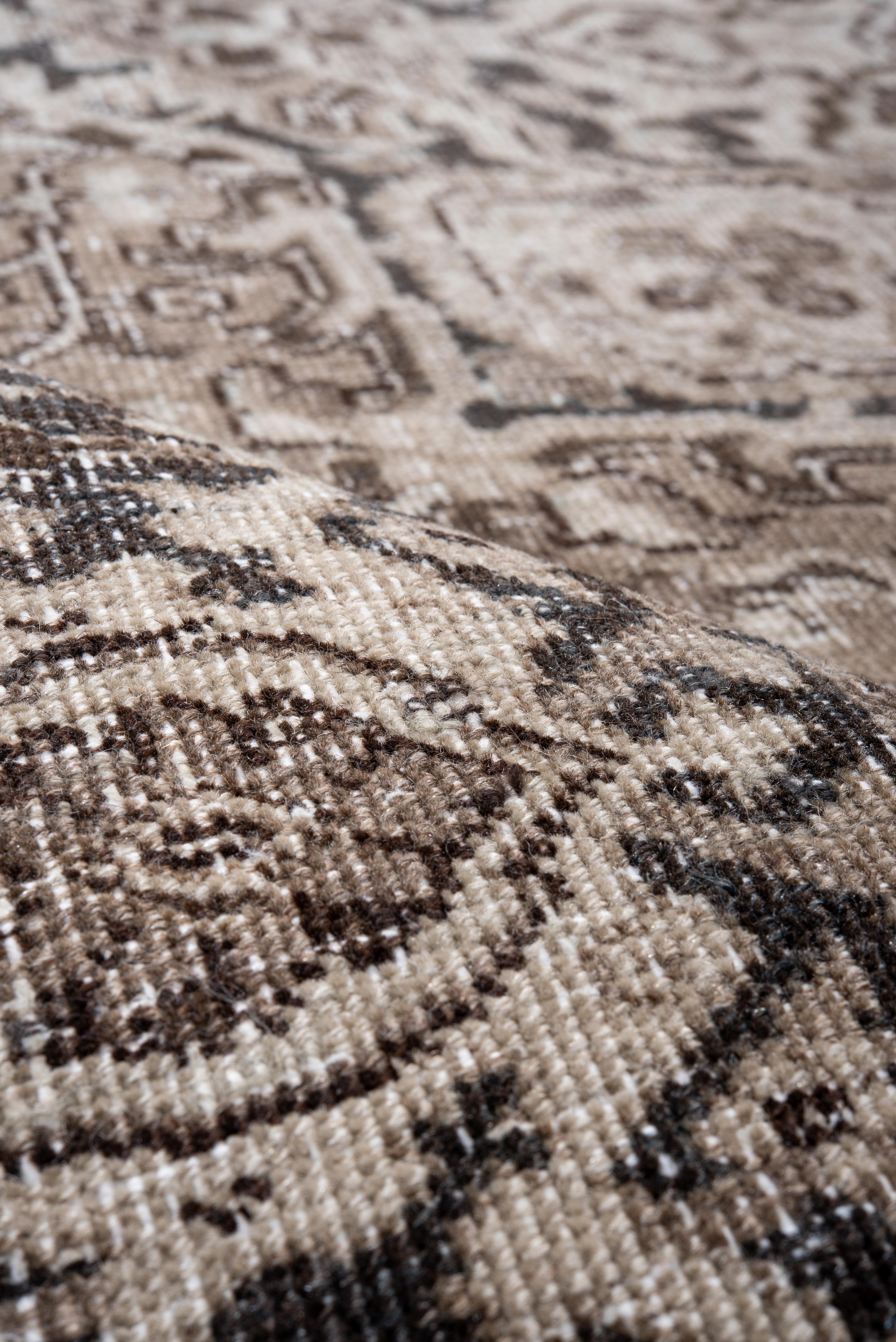 Ce tapis Heriz vintage présente un remarquable médaillon central ivoire sur un fond de noyer profond, entouré de motifs floraux anguleux et encadré d'une bordure détaillée en charbon et sable. Le médaillon en escalier et les écoinçons d'angle