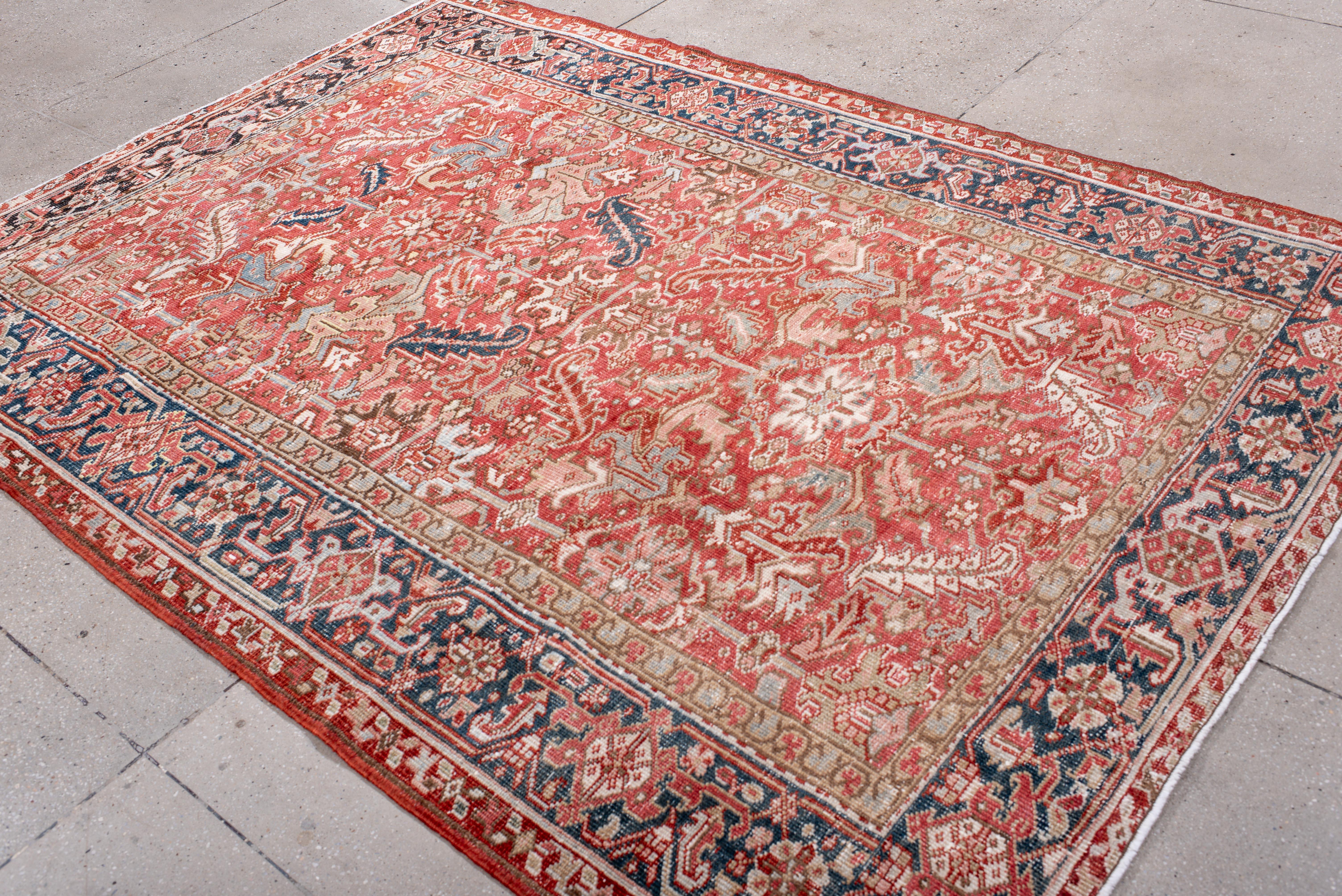 Esta alfombra Heriz vintage presenta un rico campo rojo ladrillo con un intrincado medallón floral y una decoración angular en marfil suave, melocotón pálido y añil apagado. Los toques de zafiro, óxido y salvia descolorida añaden profundidad y
