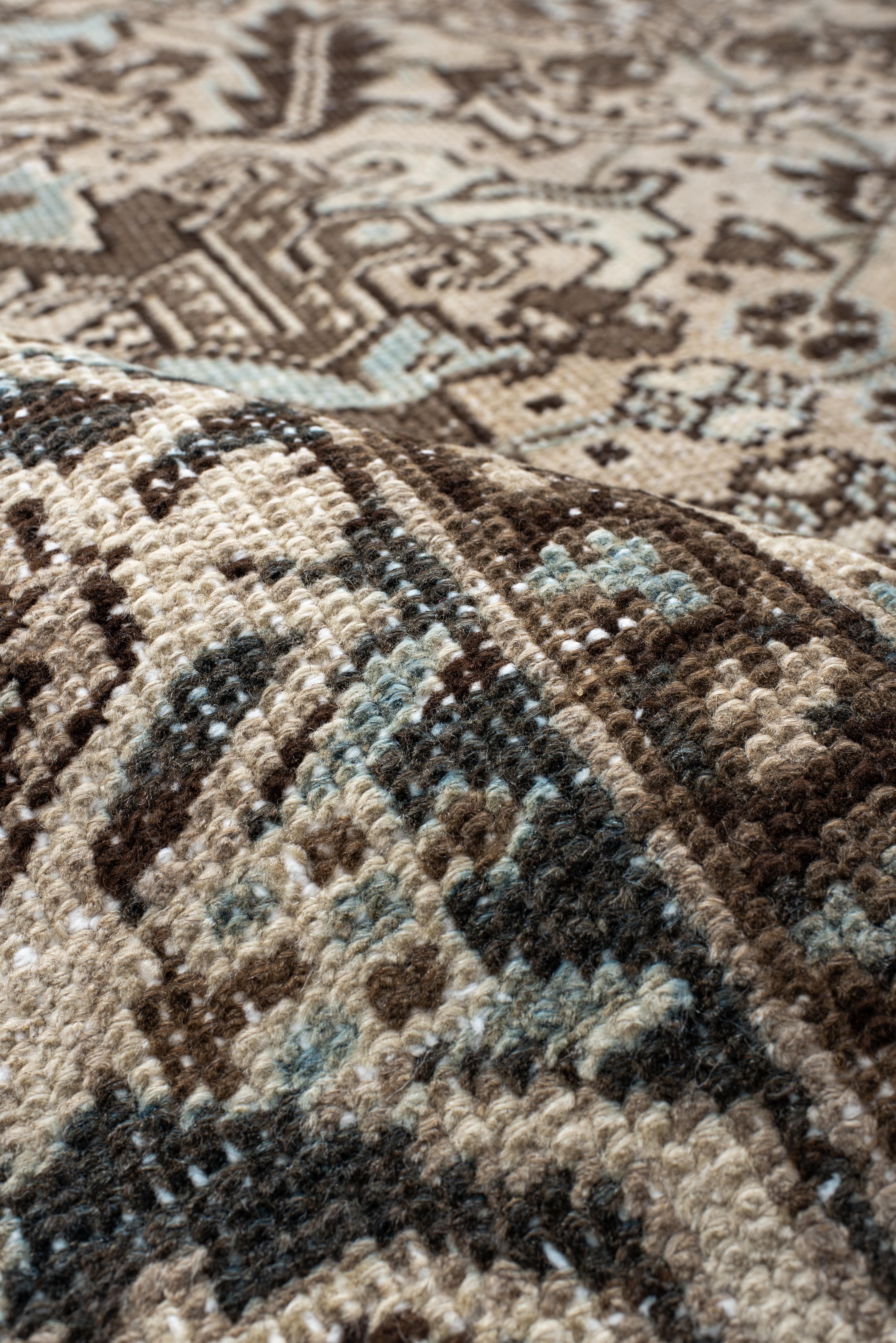 Esta alfombra Heriz vintage presenta un campo crema suavemente envejecido superpuesto con motivos angulares finamente dibujados en tonos nogal terroso y piedra pálida. En todo el diseño se entretejen detalles en azul cielo, que aportan un