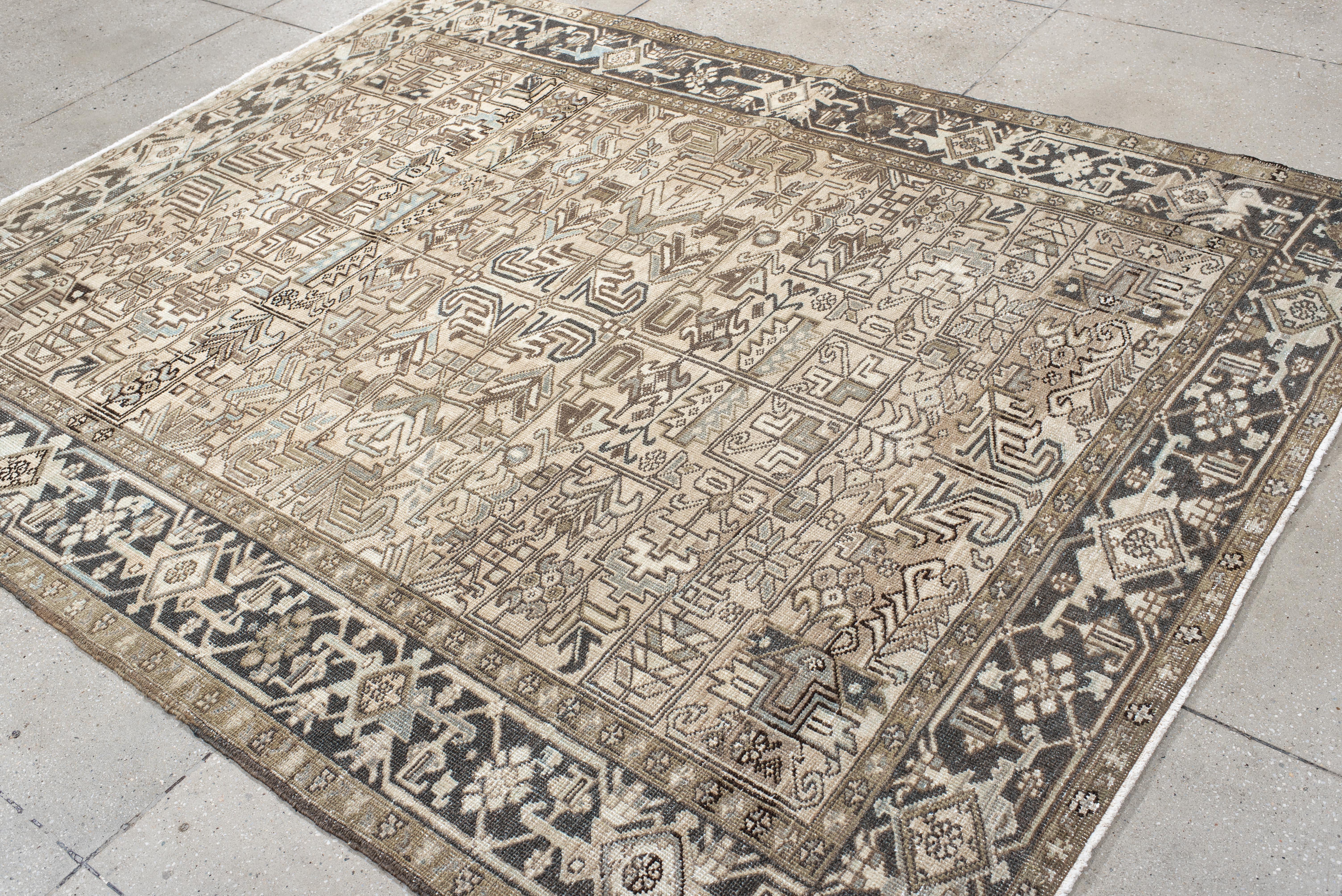 Ce tapis Heriz vintage présente un champ de couleur sable enrichi d'un treillis de motifs angulaires et de feuillages stylisés dans des tons cacao doux, taupe atténué et des touches de bleu minéral. Le motif symétrique est encadré par une bordure