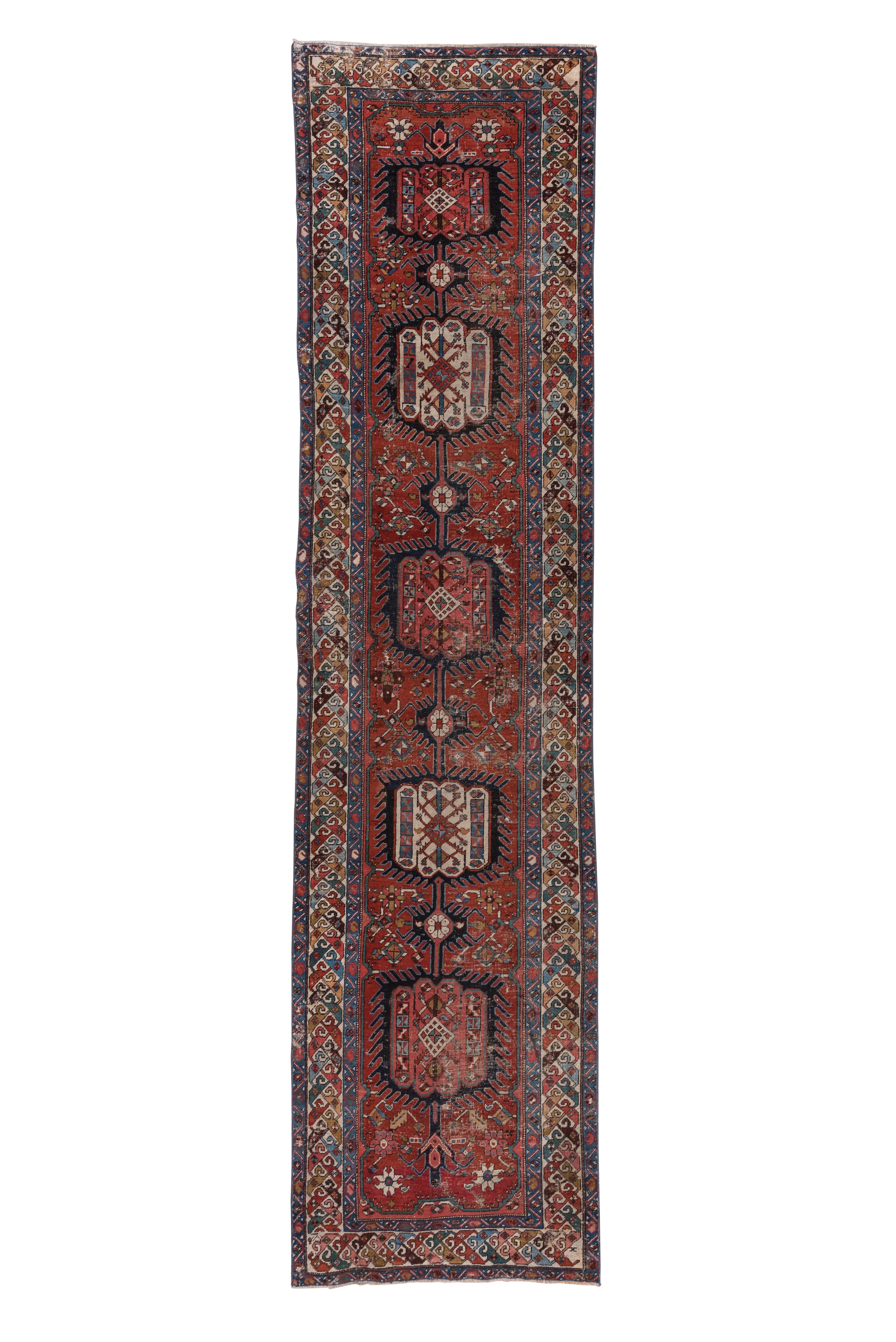Of superior Serapi grade, this NW Persian village kenare shows a natural, madder red field centred by a five section pole medallion. Each rounded cartouche-like segment has a finger fringe surrounding it and is accented in ecru and buff-camel. Small